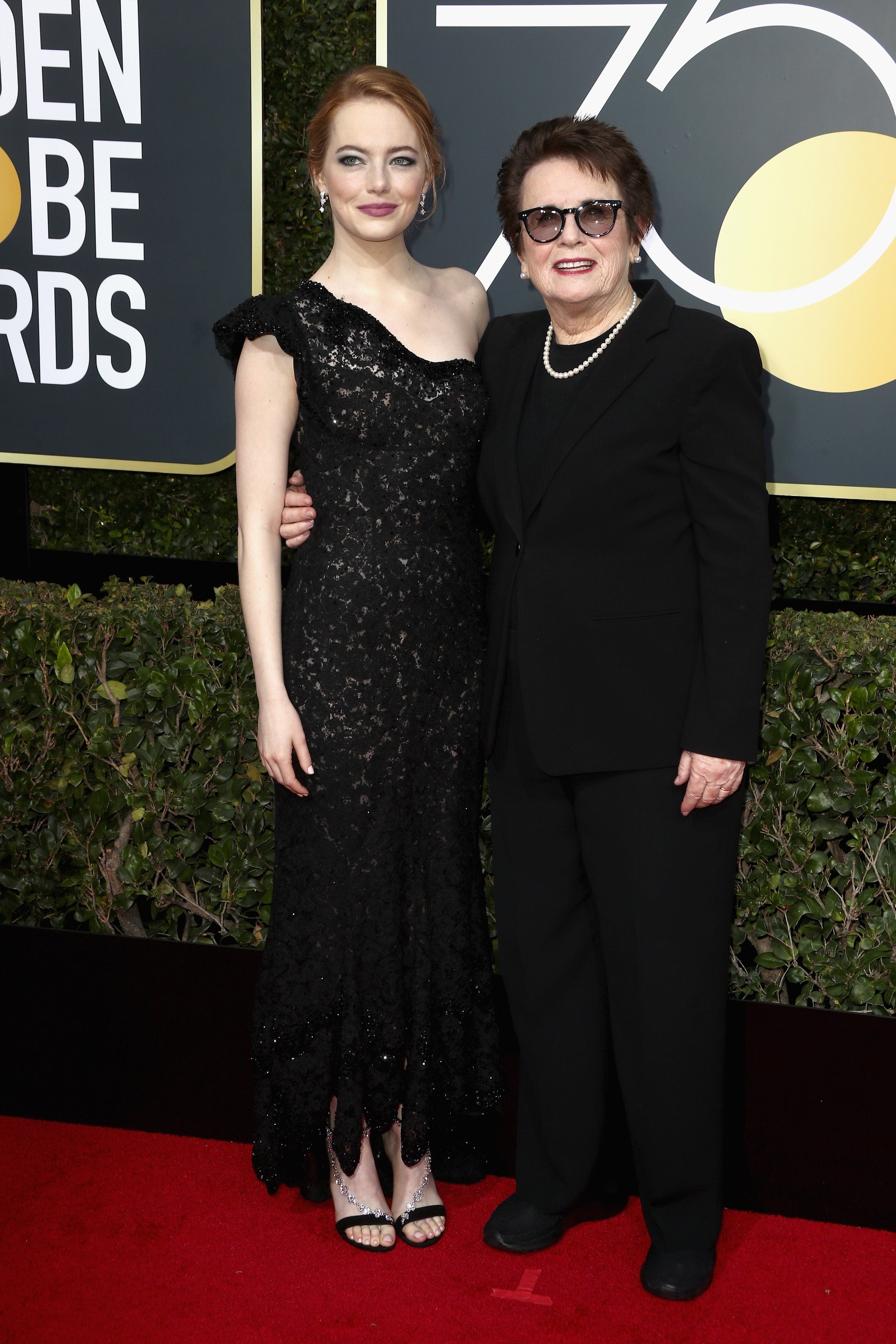 Emma Stone and Billie Jean King smile beside one another on the 2018 Golden Globes red carpet.