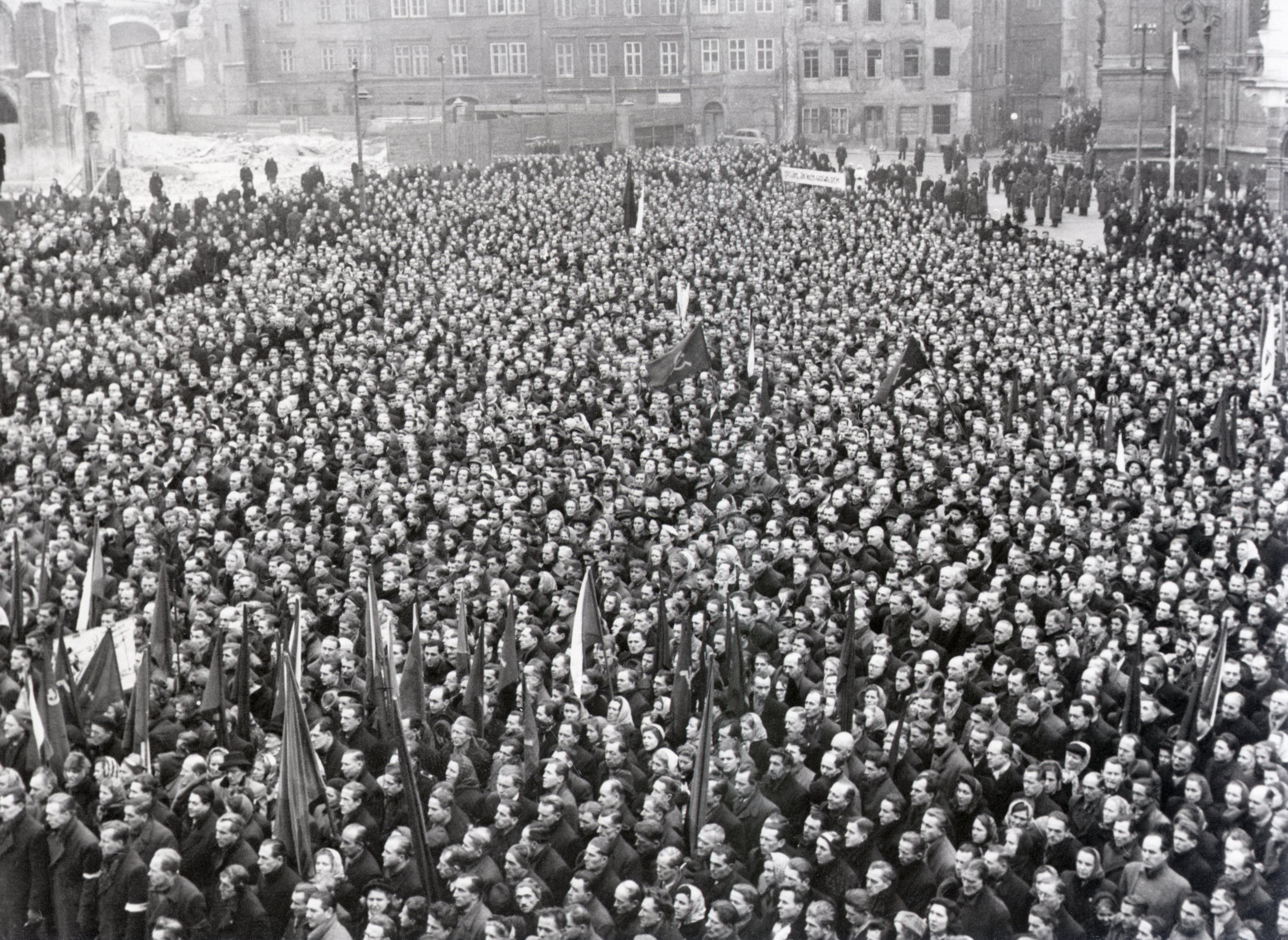 Large crowd gathered in a historical black-and-white photo, holding flags and banners