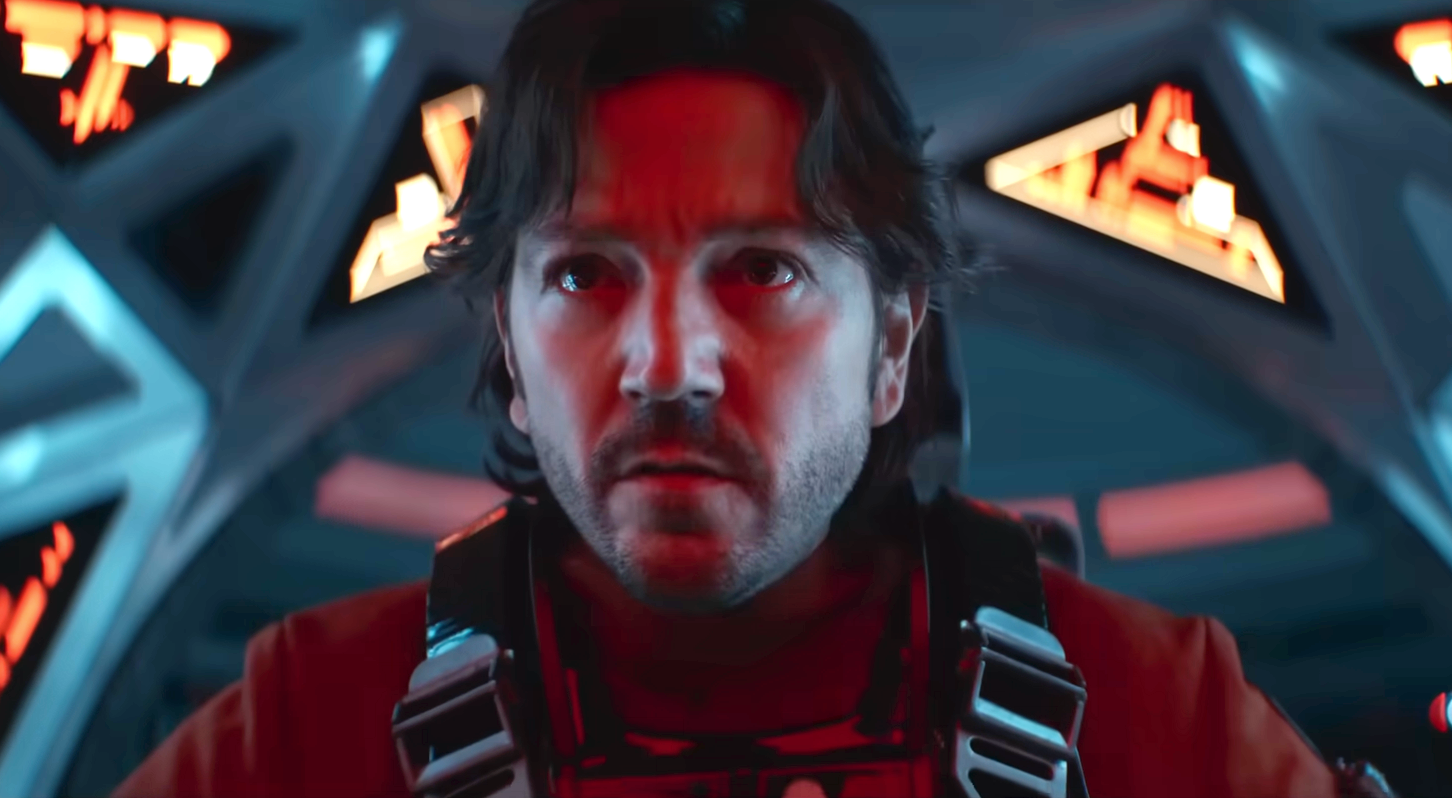 A person in a sci-fi setting, wearing a futuristic outfit with an intense expression, sits in a high-tech cockpit