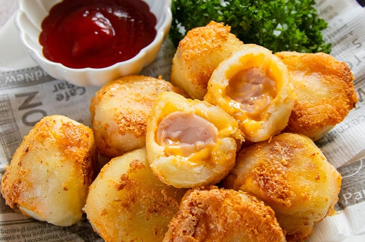 ポテトボールが皿に盛られ、横にパセリとケチャップが添えられている。ボールは中にチーズとソーセージが入っている。