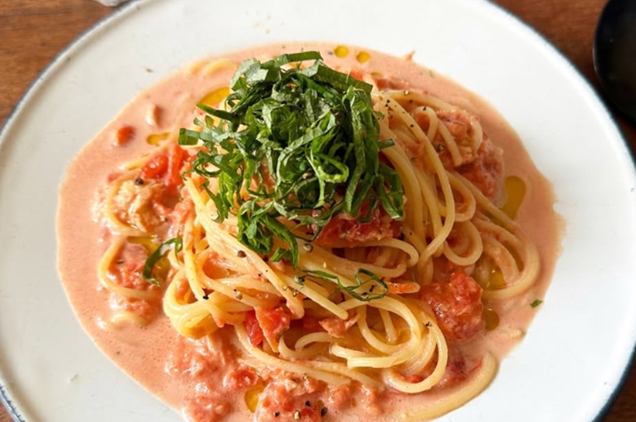 クリーミーなトマトソースのスパゲッティ、刻んだハーブがトッピングされた一皿。