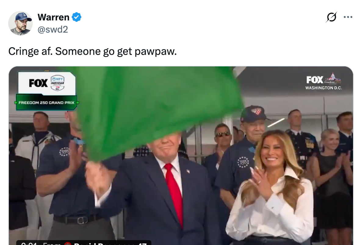 Tweet viser en person i dress som vifter med et grønt flagg på et FOX-arrangement, med en kvinne i en hvit bluse som smiler i nærheten. Tekst: "Cringe af. Noen går og henter pawpaw."