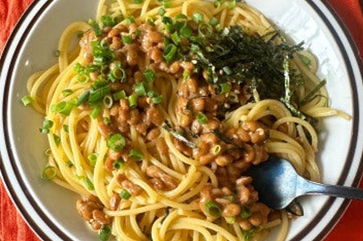 皿に盛られた納豆パスタ。青ねぎと海苔がトッピングされ、フォークが横に添えられている。
