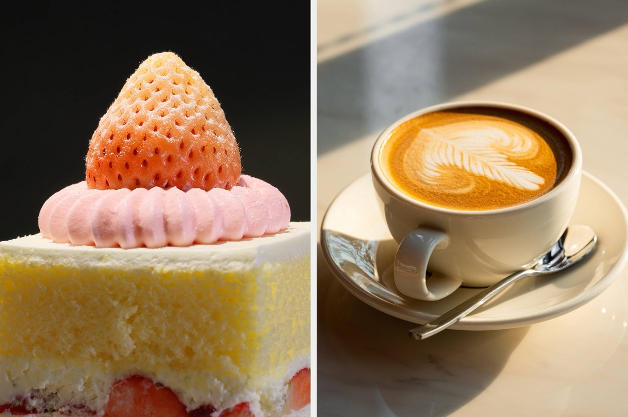 A cake with a white strawberry on top next to a cup of latte with latte art, placed on a table with a spoon