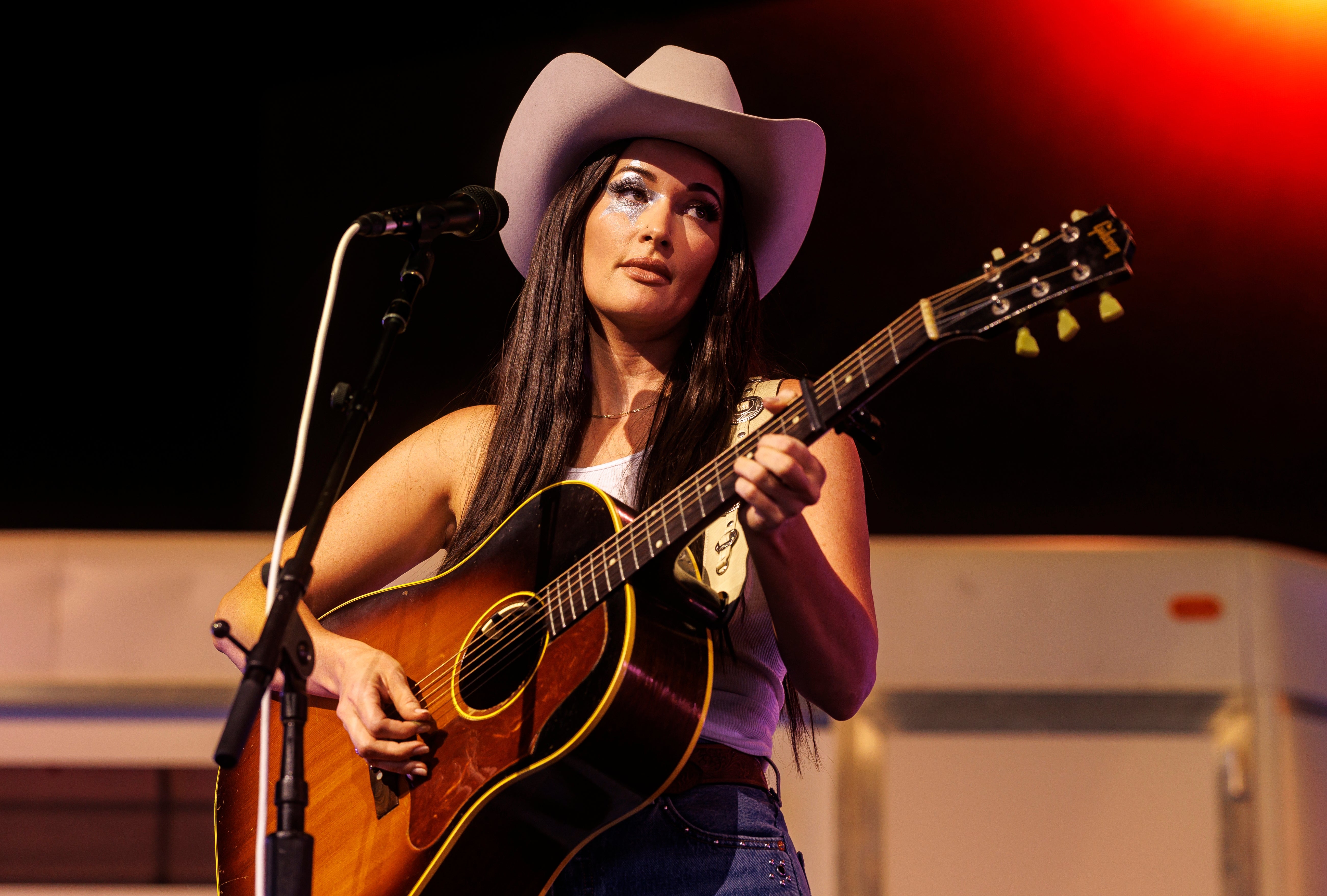 Person i cowboyhatt som spiller en akustisk gitar på scenen