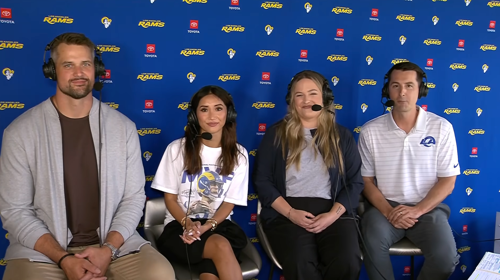 Four sports commentators with headsets sit together in front of a Rams-branded backdrop