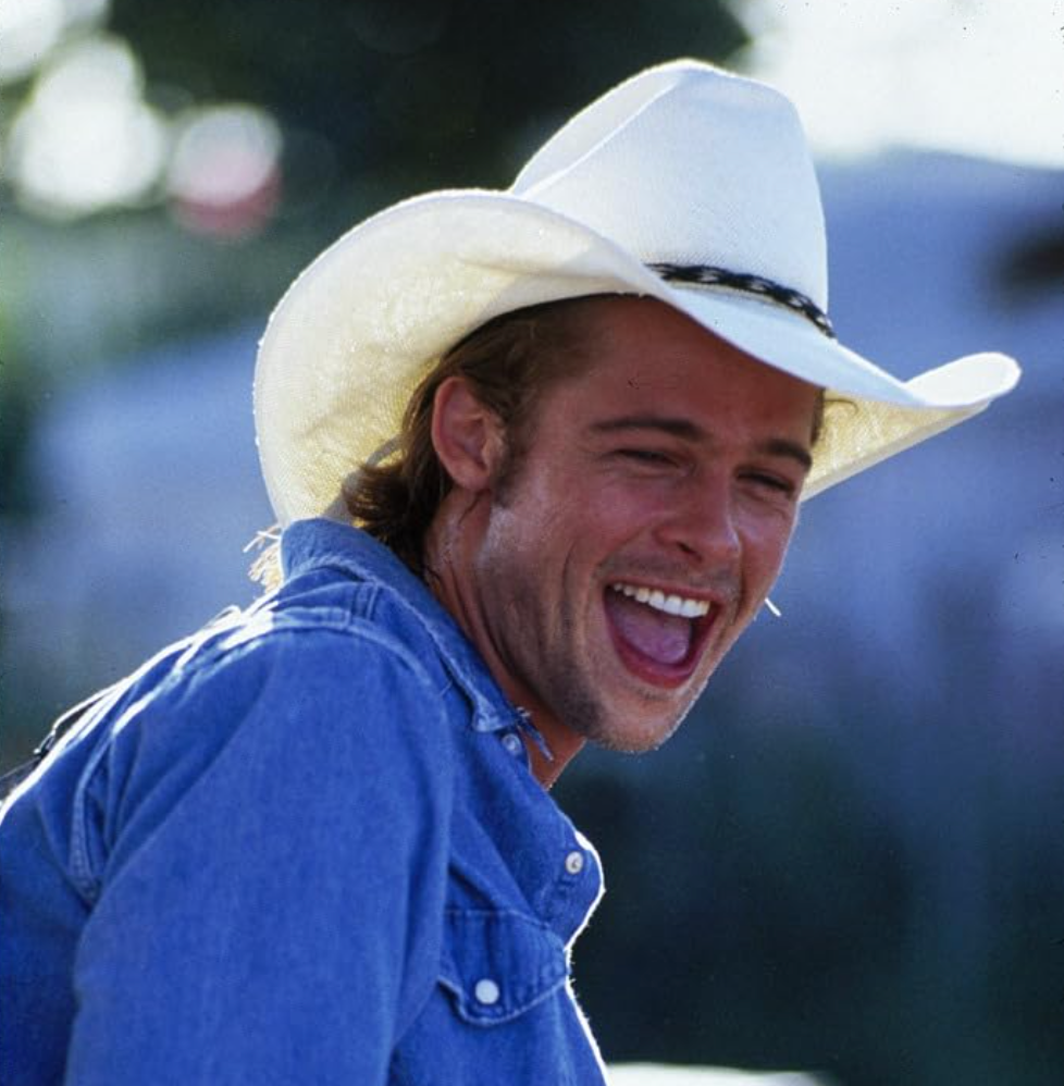 Person smiling, wearing a cowboy hat and denim jacket, appearing casual and joyful
