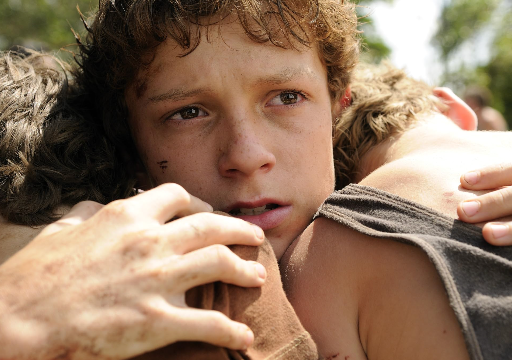 A young person tightly embraces two others, displaying concern and vulnerability. They appear to be in an emotional or intense moment