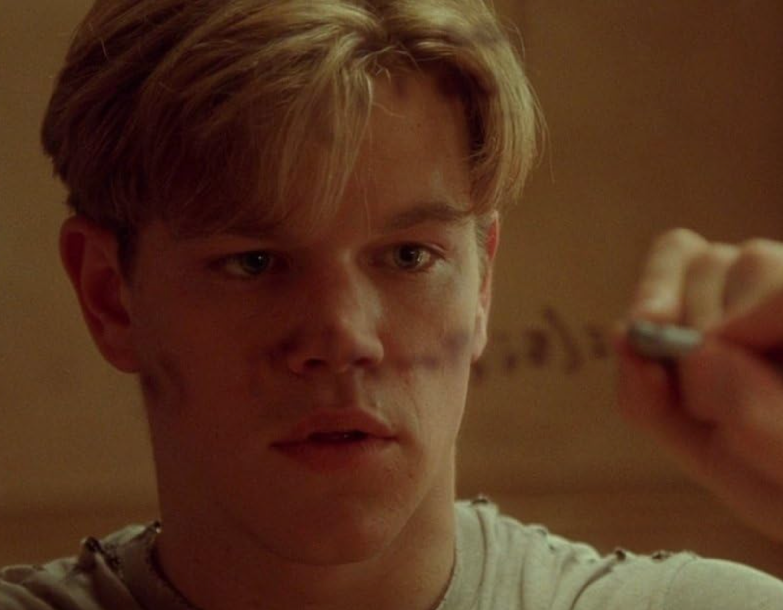 A man is intensely writing on a window with a marker, appearing focused and thoughtful