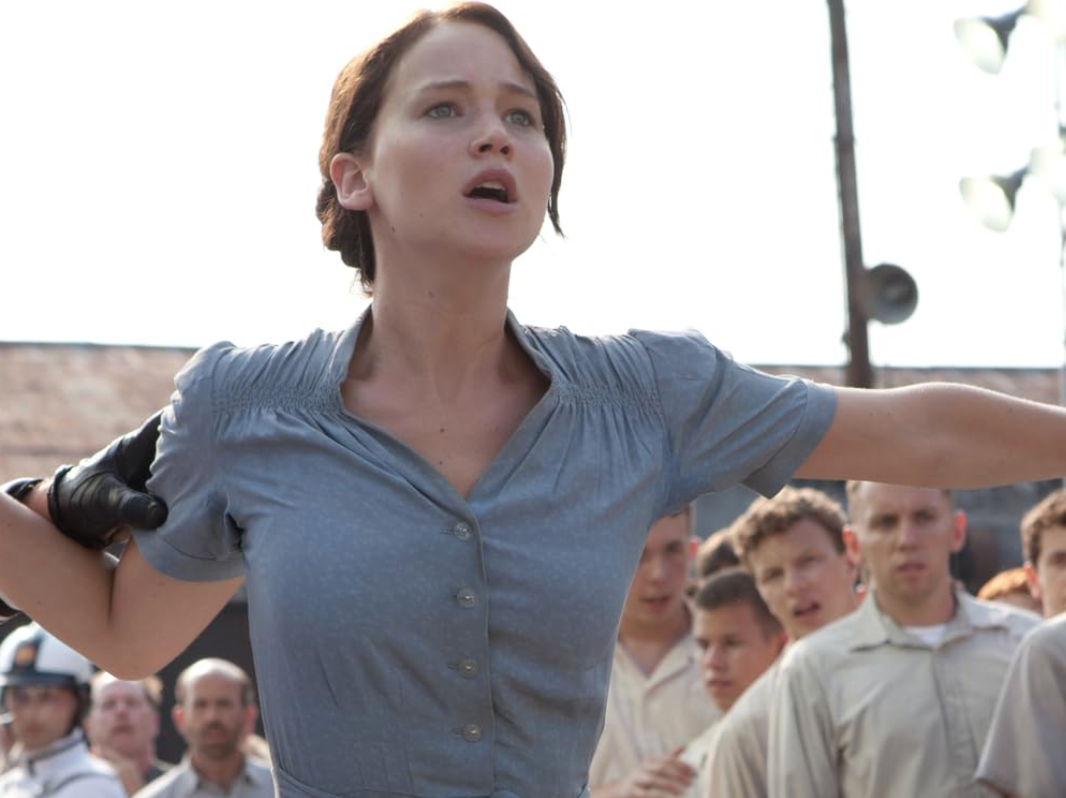 Person with arms outstretched, expressing defiance amidst a crowd in a dramatic scene