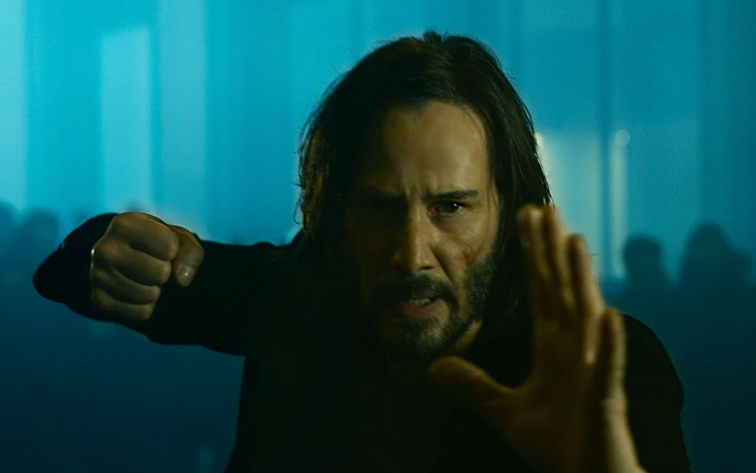 A person extends one hand forward and makes a fist with the other, standing in a determined pose in a dramatic setting