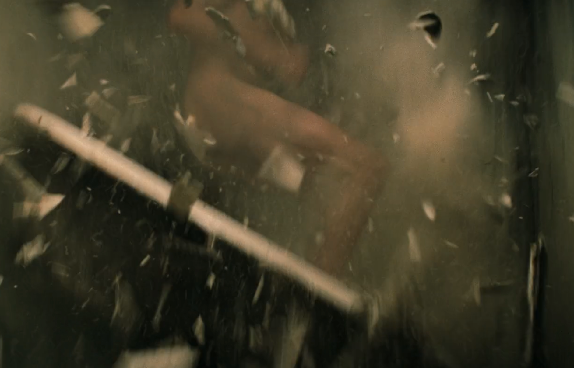 A person crashes through a wall amid flying debris, capturing a dynamic action scene