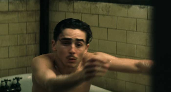 Person in a bathtub reaching out urgently, appearing distressed. The setting is a vintage-style bathroom