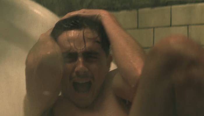 Person in a bathtub holding their head, appearing distressed and screaming