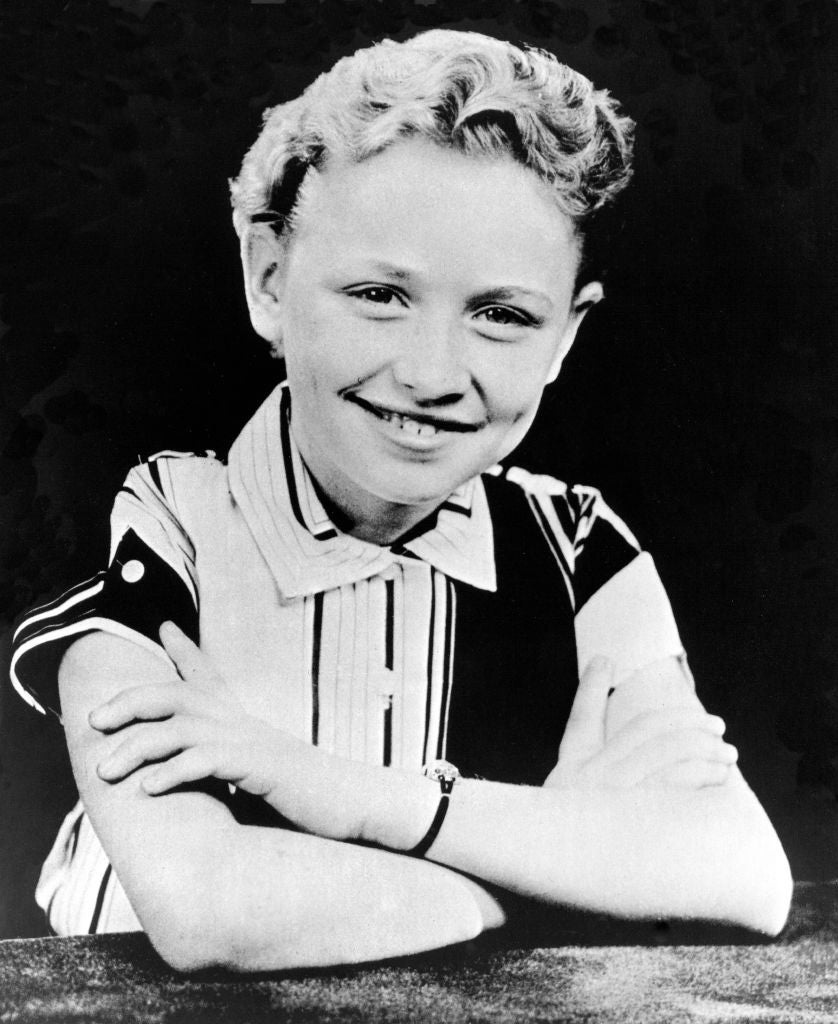 Smiling child with short hair, wearing a striped shirt, arms crossed