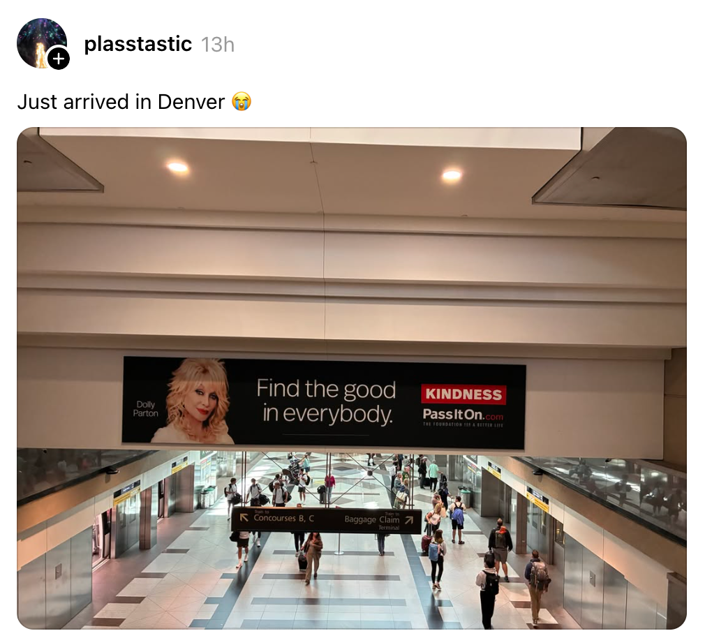 Airport scene with a Kindness PassItOn.com banner featuring Dolly Parton, saying "Find the good in everybody." Travelers walk below