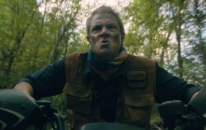 Person riding an Arctic Cat ATV through a forest, looking determined