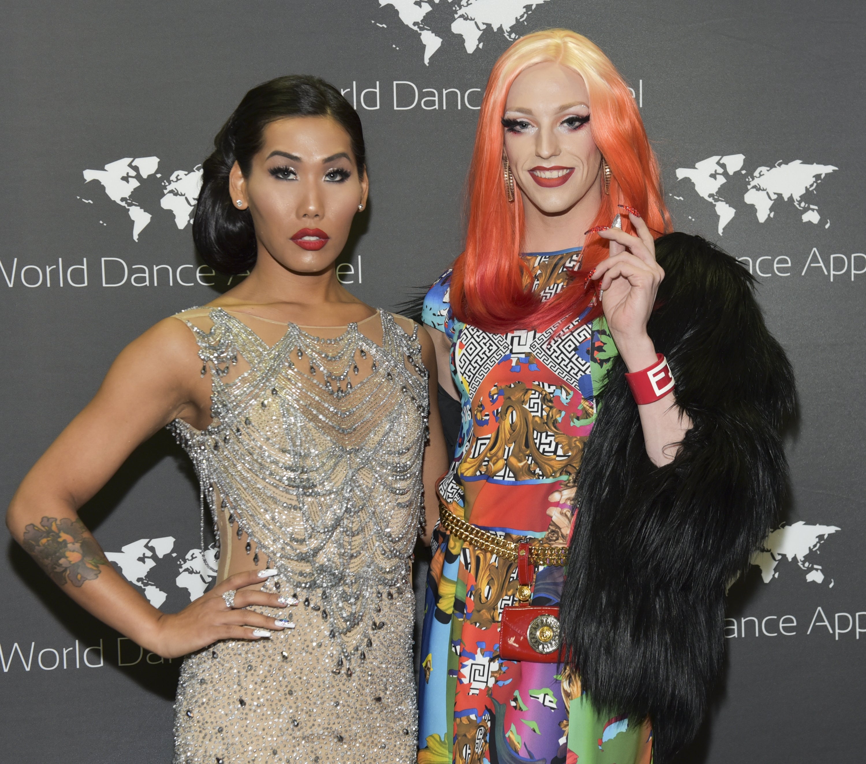 Two people at a World Dance Appeal event; one in a bejeweled gown, the other in colorful, patterned attire with a fur accessory