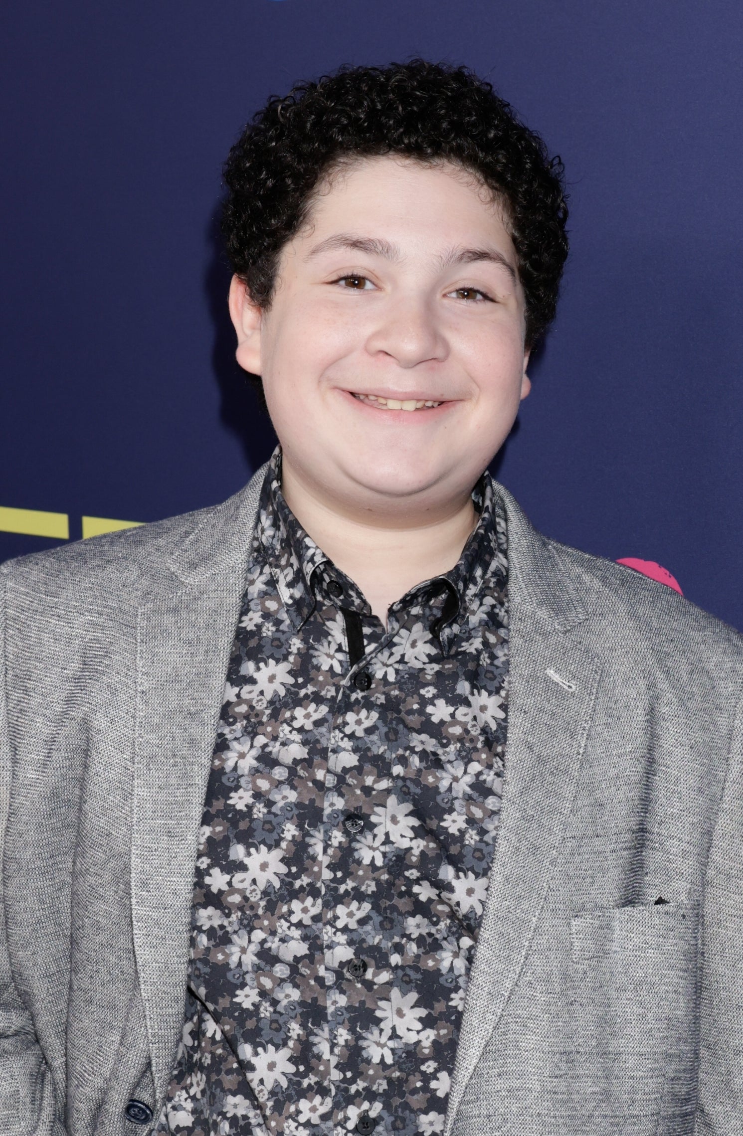 Person in a floral shirt and a gray blazer poses at a CBS event