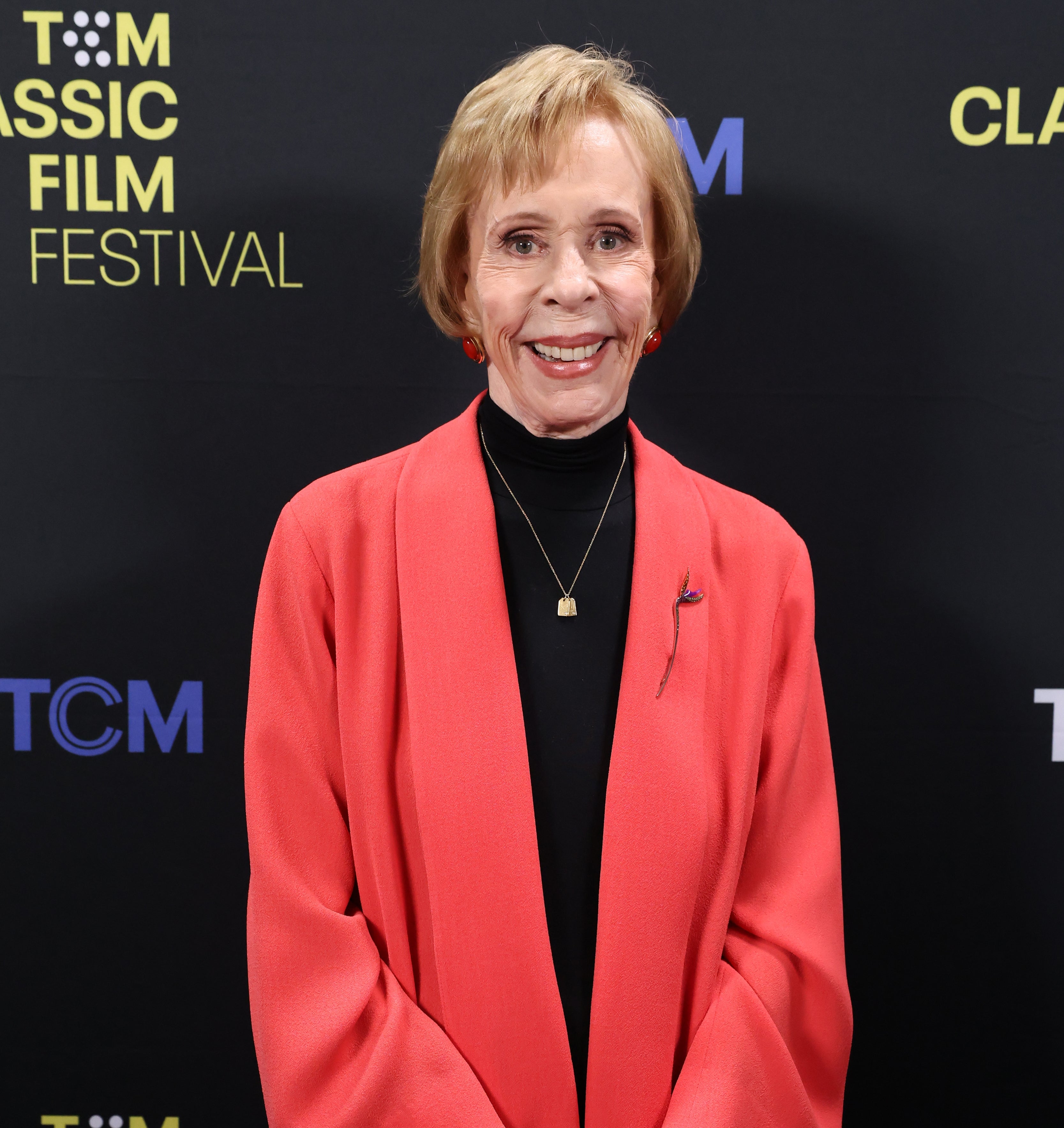Person in a red jacket and black top smiling at the TCM Classic Film Festival