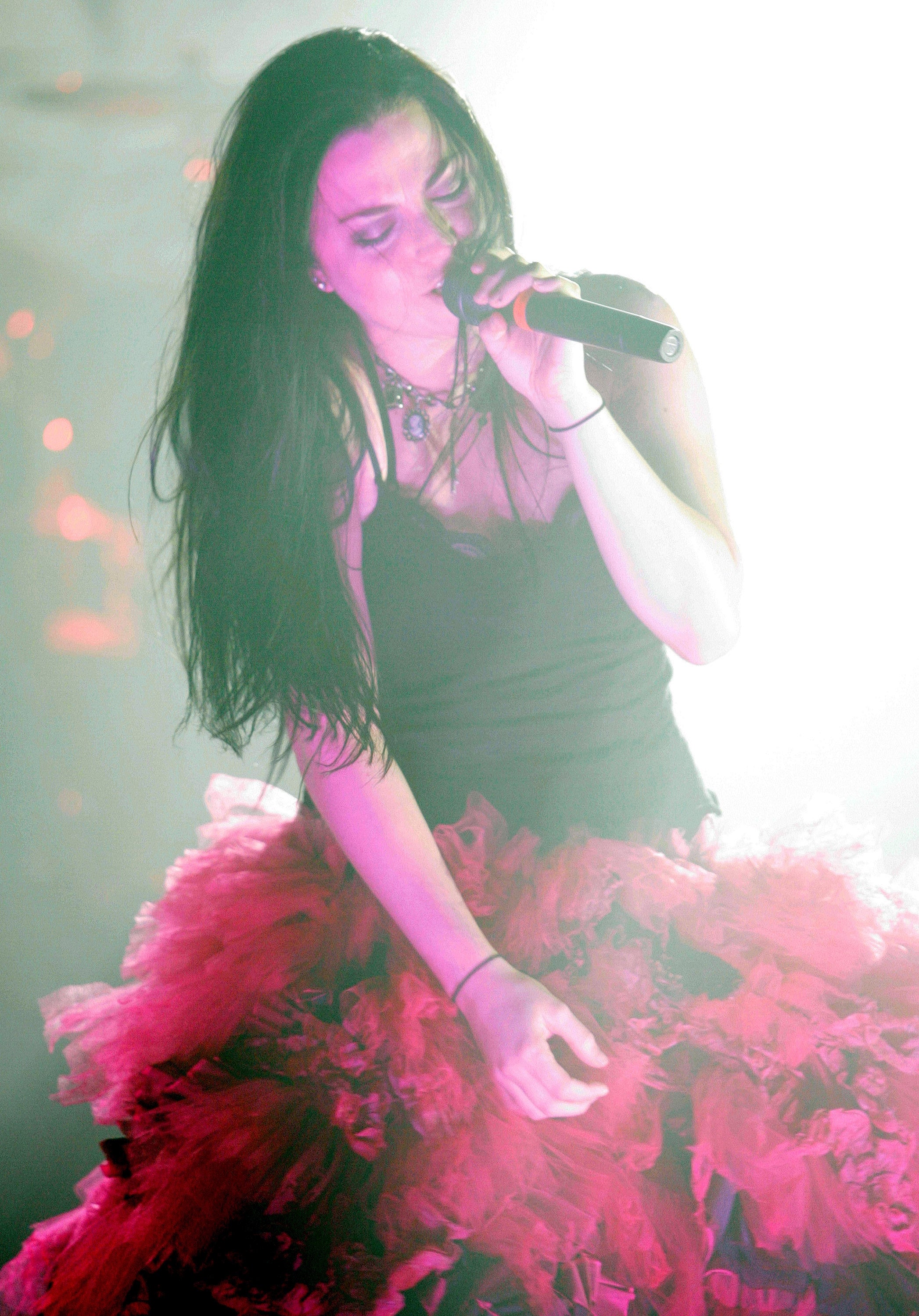 Singer performing on stage, wearing a dramatic, layered tulle skirt and a sleeveless top, holding a microphone