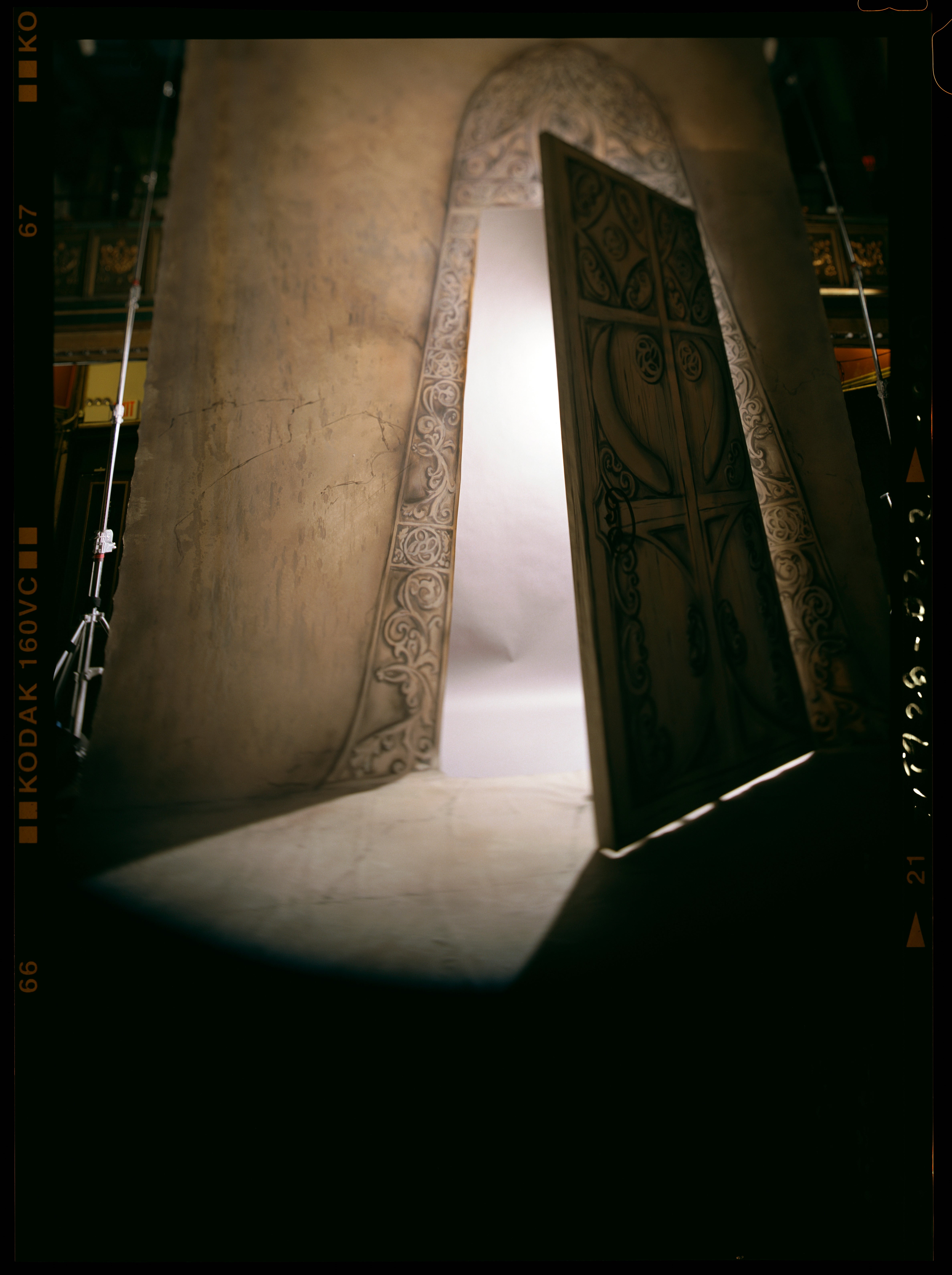 Ornate, slightly open door with intricate carvings, casting light into the dark room