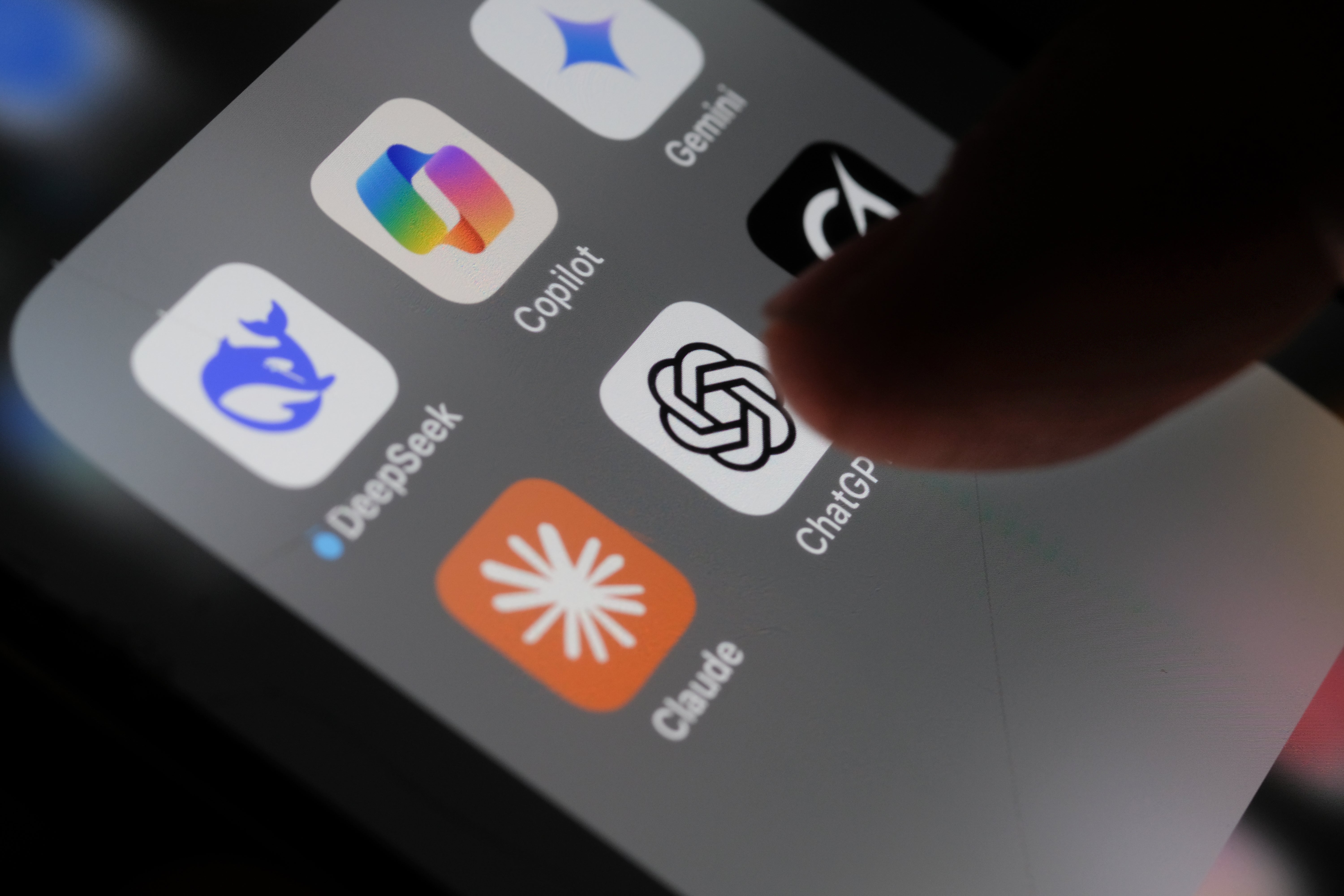 Finger pointing at ChatGPT app icon on a smartphone screen, surrounded by other app icons