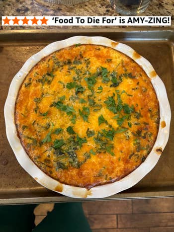 Baked quiche in a round dish topped with herbs, placed on a baking tray