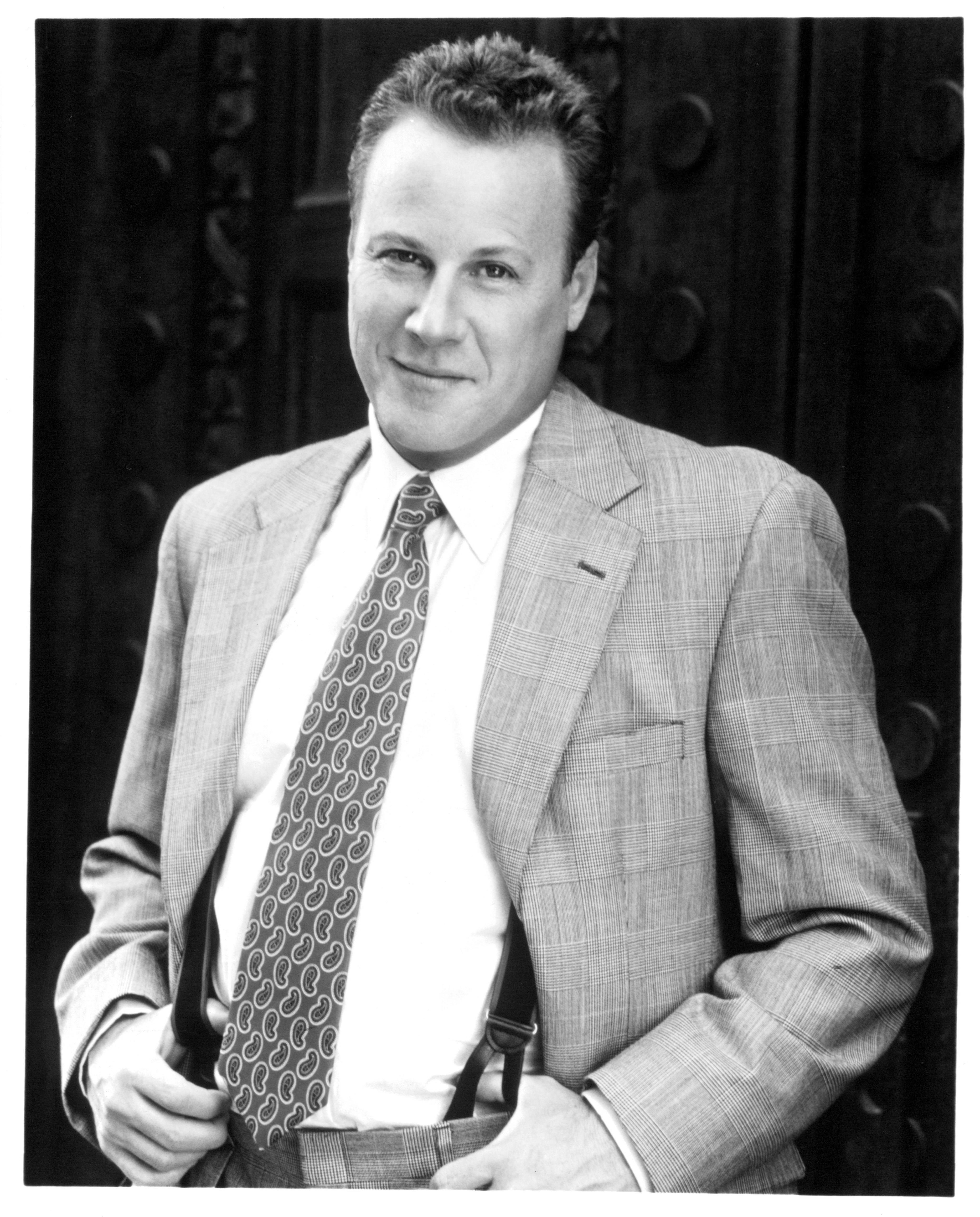 Person in a tailored plaid suit with a patterned tie, standing confidently with hands in pockets