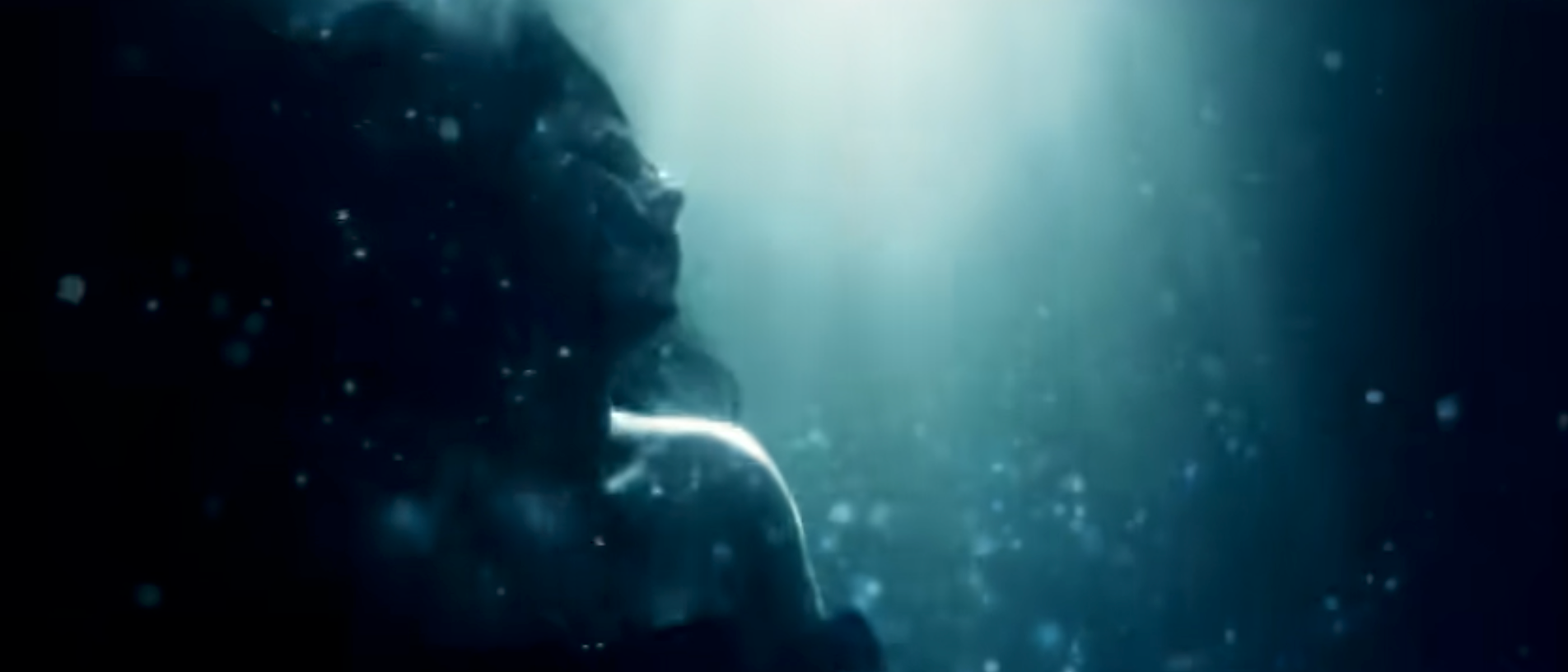 Silhouette of a person submerged in water, with bubbles and light creating a serene, ethereal atmosphere