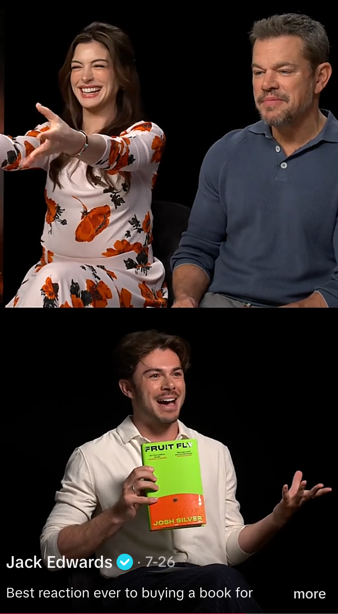 Two people smile during an interview, one wearing a floral-patterned outfit. Below, a person excitedly holds a book titled "Fruit Fly" by Josh Silver