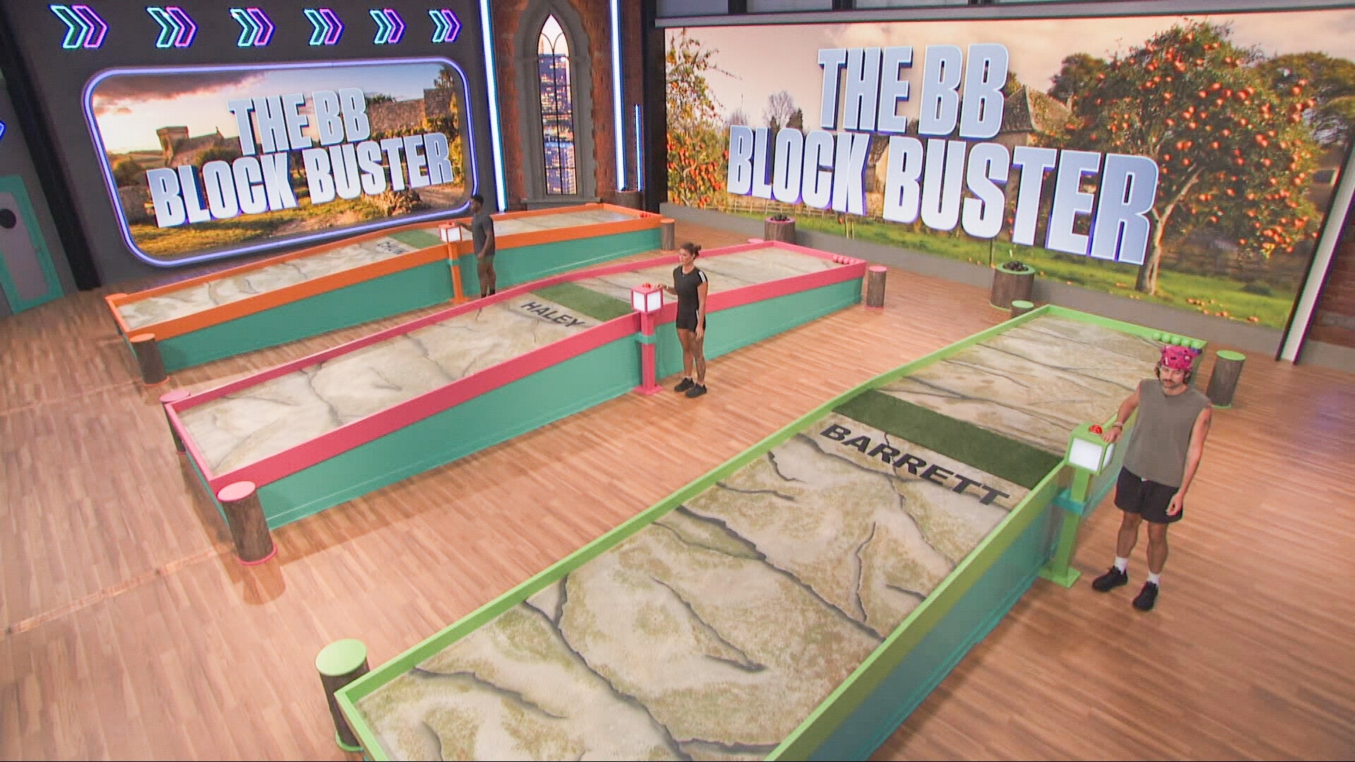 "Big Brother" contestants compete in the Block Buster game on a set with large signs and gameboards