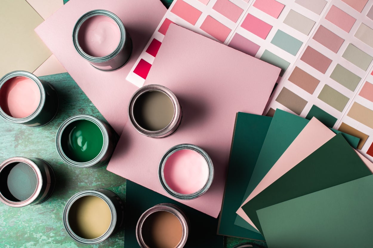 Open paint cans and color swatches arranged over a table, showcasing a variety of shades and palettes for design inspiration