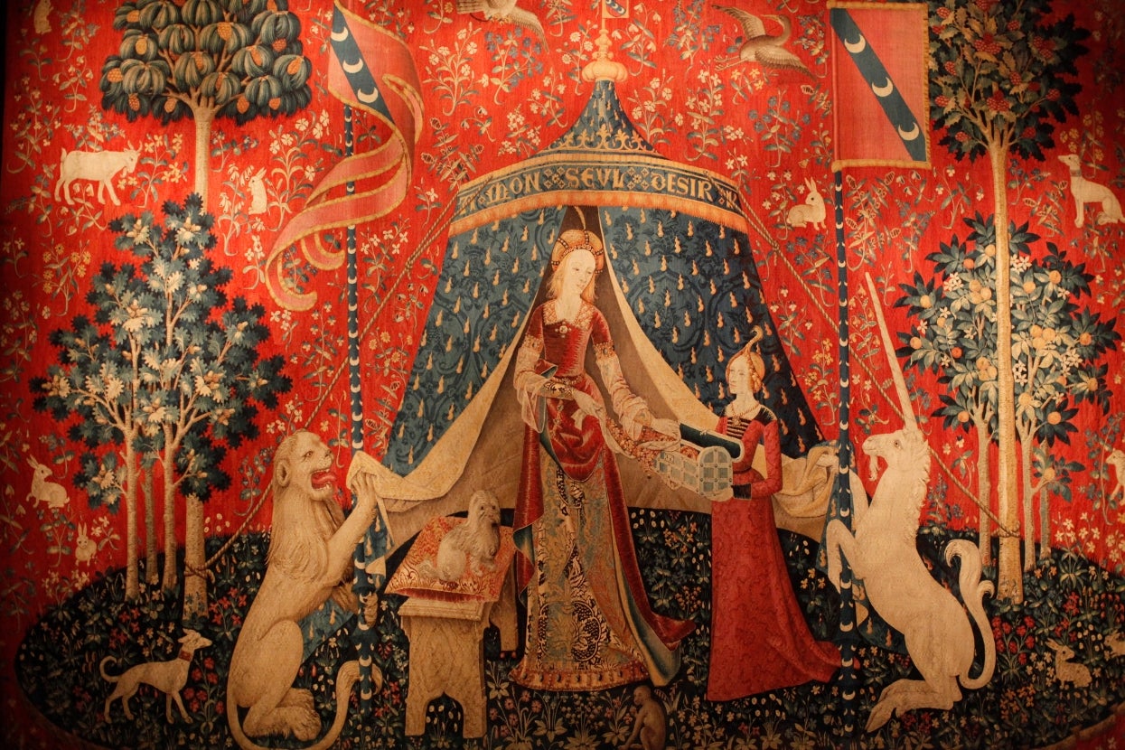 Medieval tapestry depicting a lady with a unicorn and lion, surrounded by trees and animals, showcasing intricate patterns and storytelling