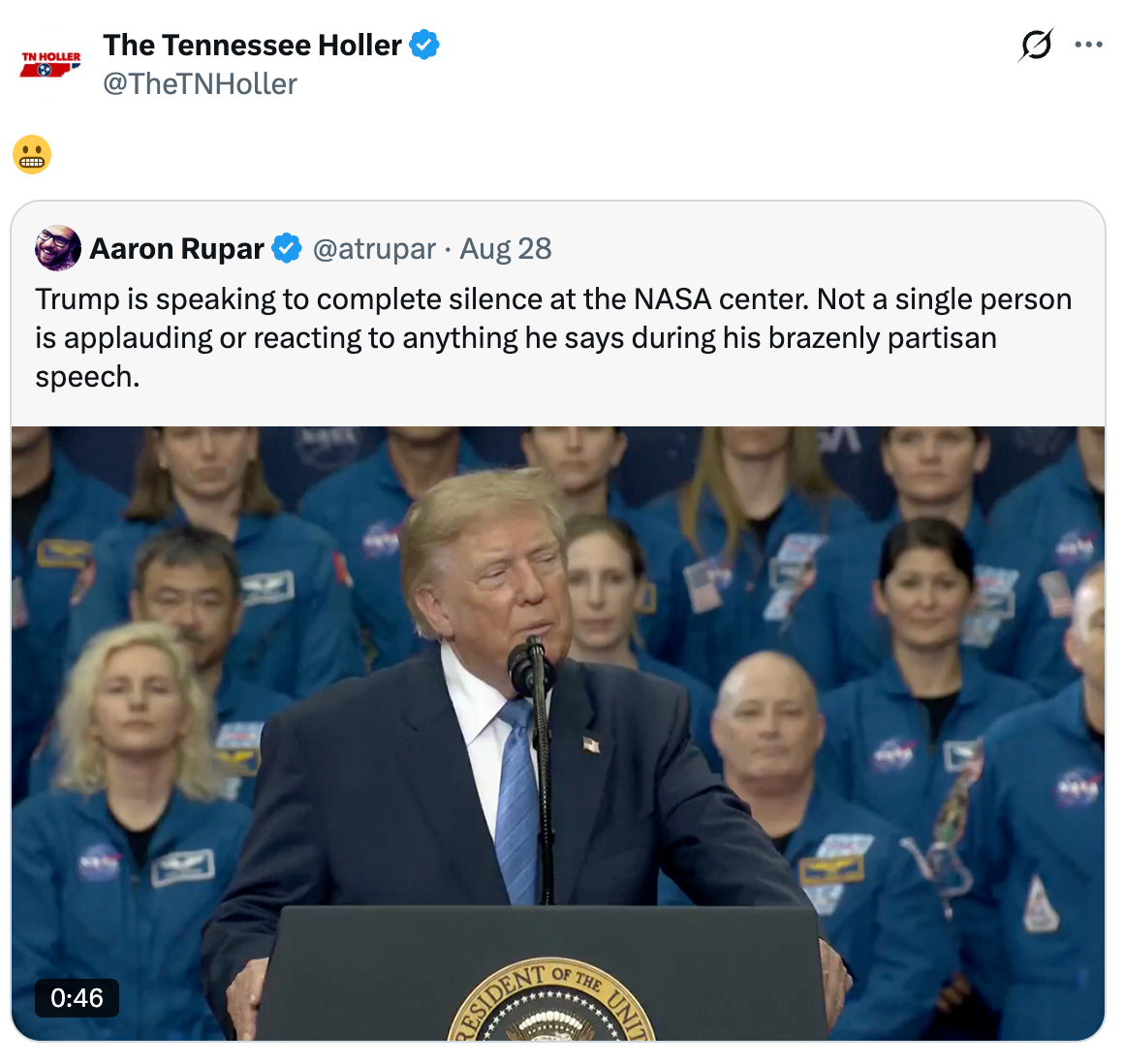Donald Trump taler ved et podium i et NASA-senter, med et publikum i blå uniformer bak seg, og virker taus