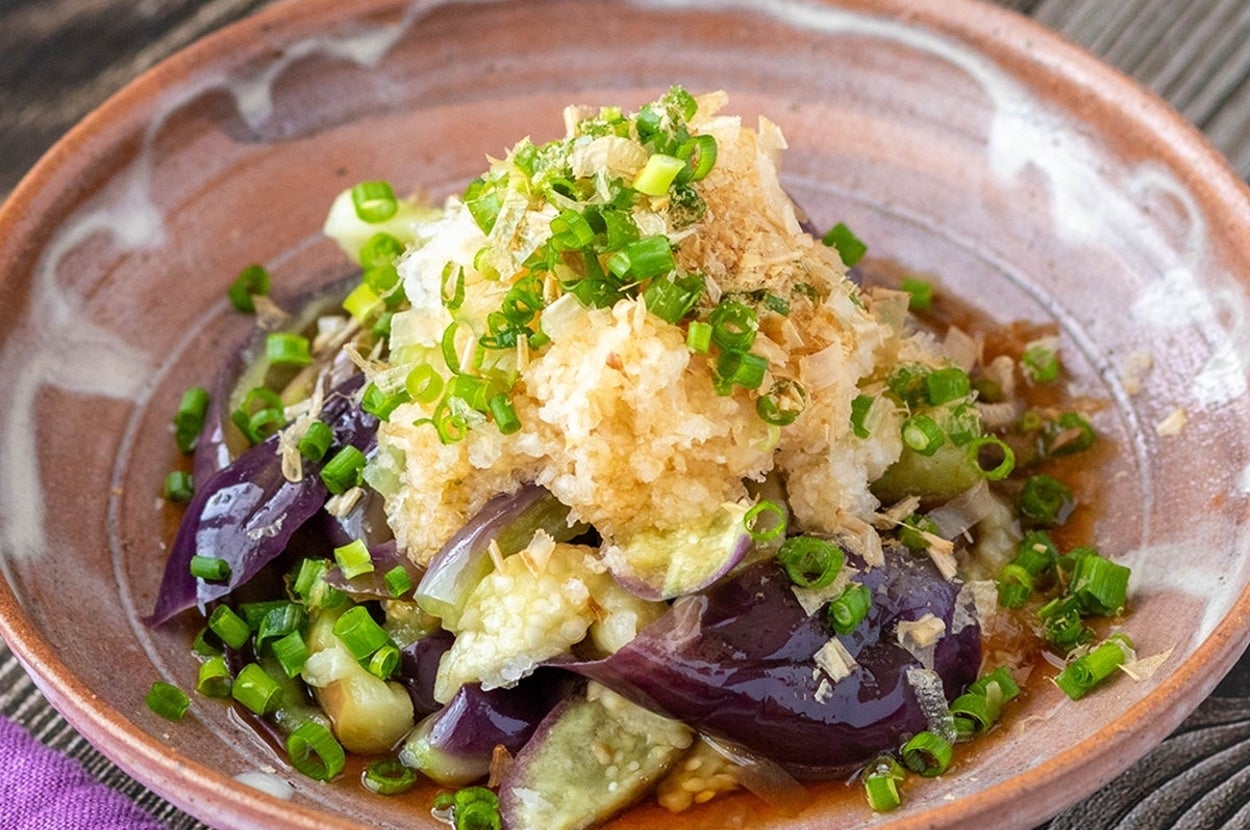 和風の皿に盛られた揚げ茄子とおろしポン酢ソースの料理。細かく刻んだネギがトッピングされている。