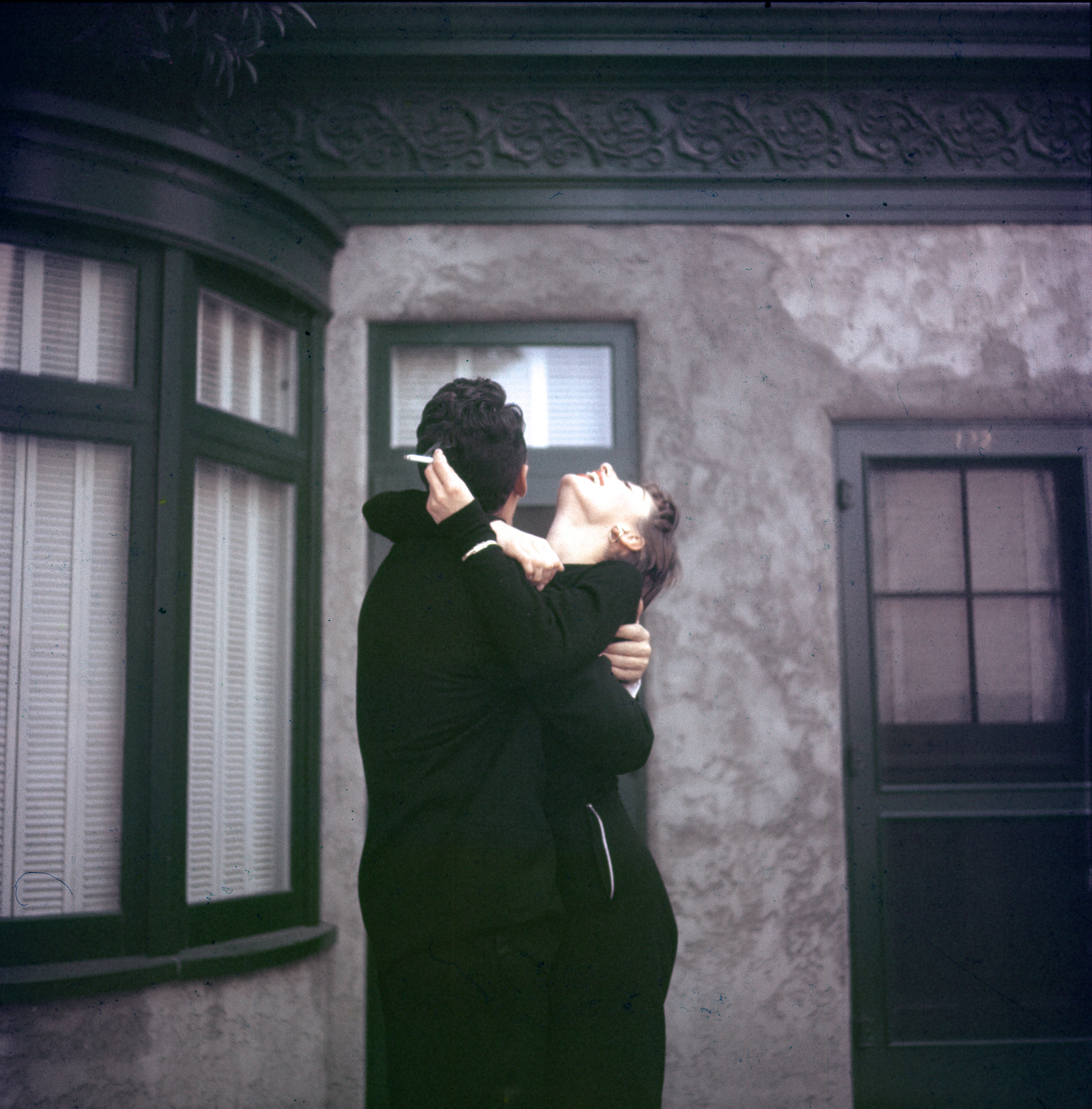 Audrey and Dean Martin romantically outside a building, their faces turned upwards, with an artistic, vintage feel to the scene