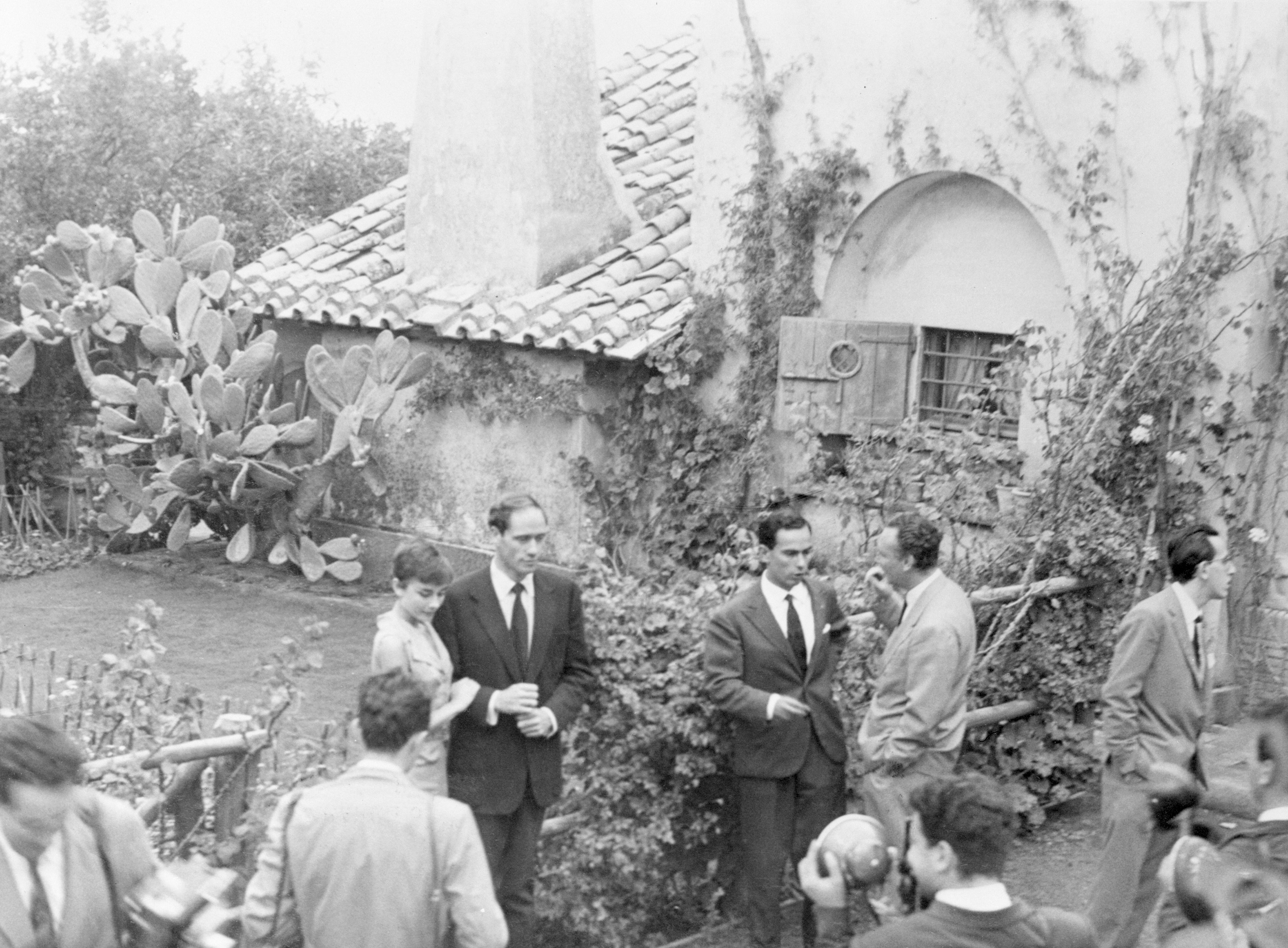 Group gather outside a rustic house with a tiled roof