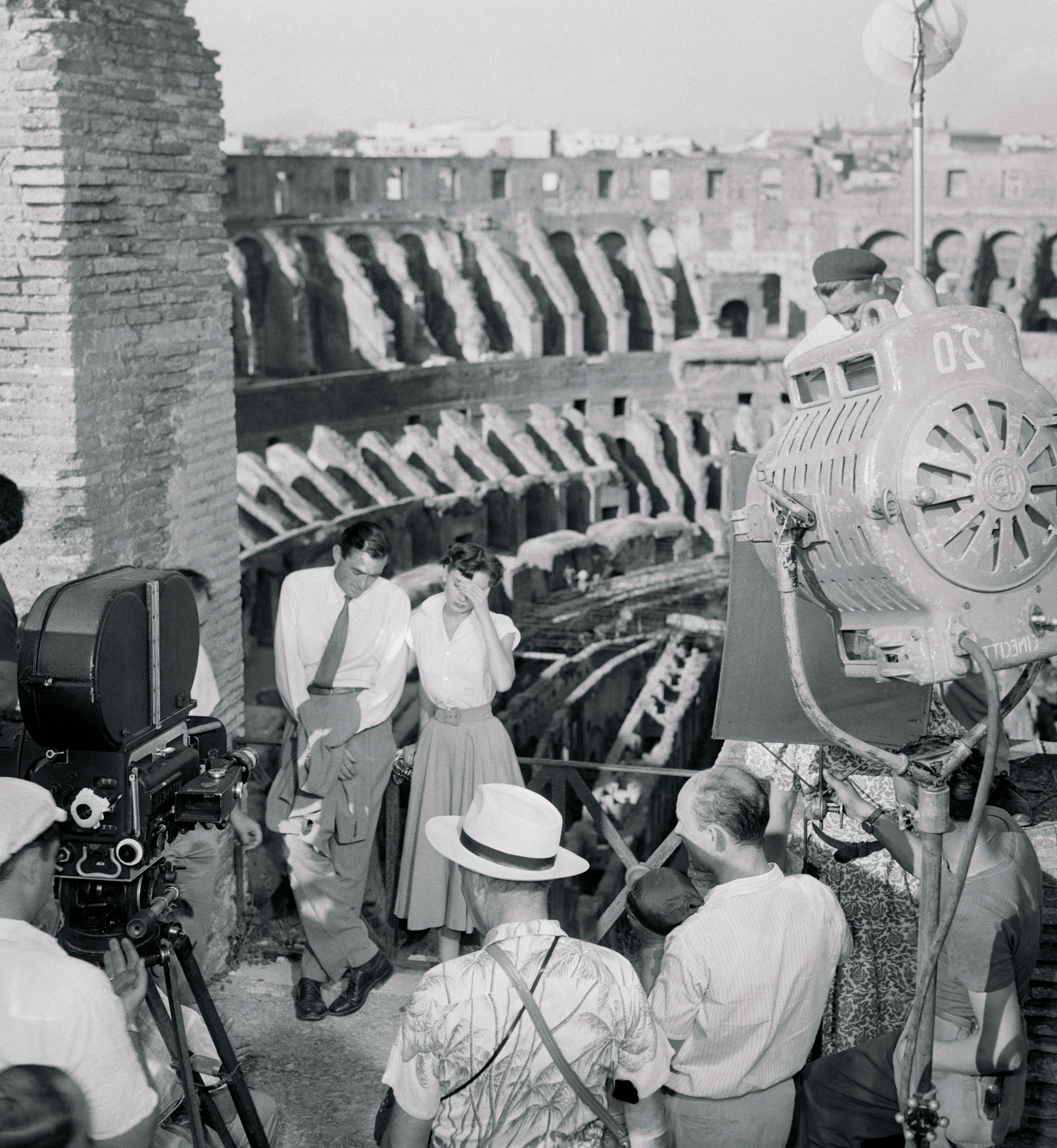 Film crew and actors on set at the Colosseum, with large cameras and equipment around them, capturing a scene
