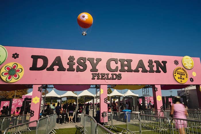 "Entrance to Daisy Chain Fields festival with a hot air balloon overhead and people entering the event area."