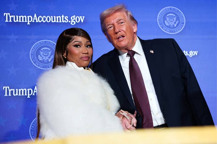 I don’t know who these individuals are, but the image shows two people on stage with the background displaying "TrumpAccounts.gov." One wears a fur coat
