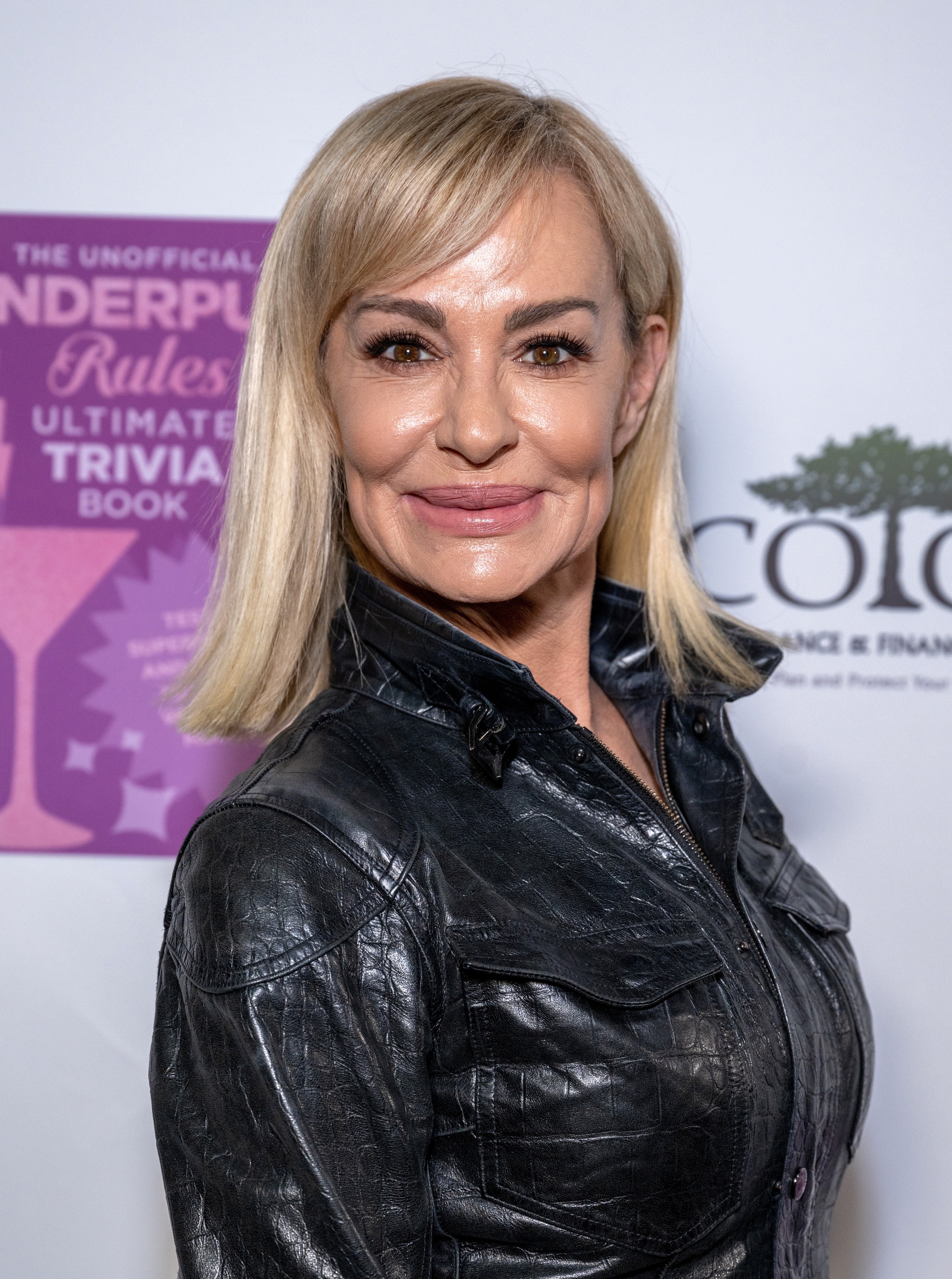 Person in sleek leather jacket on a media backdrop at an event