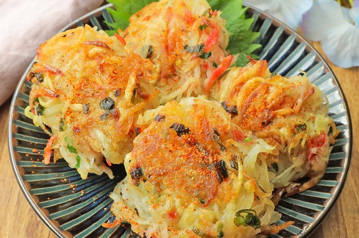 和風の皿に盛られた揚げ野菜かき揚げが、葉の上に美しく配置されている。