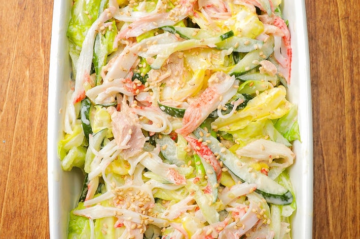 新鮮な野菜とカニがたっぷり入ったサラダが白い皿に盛られている。