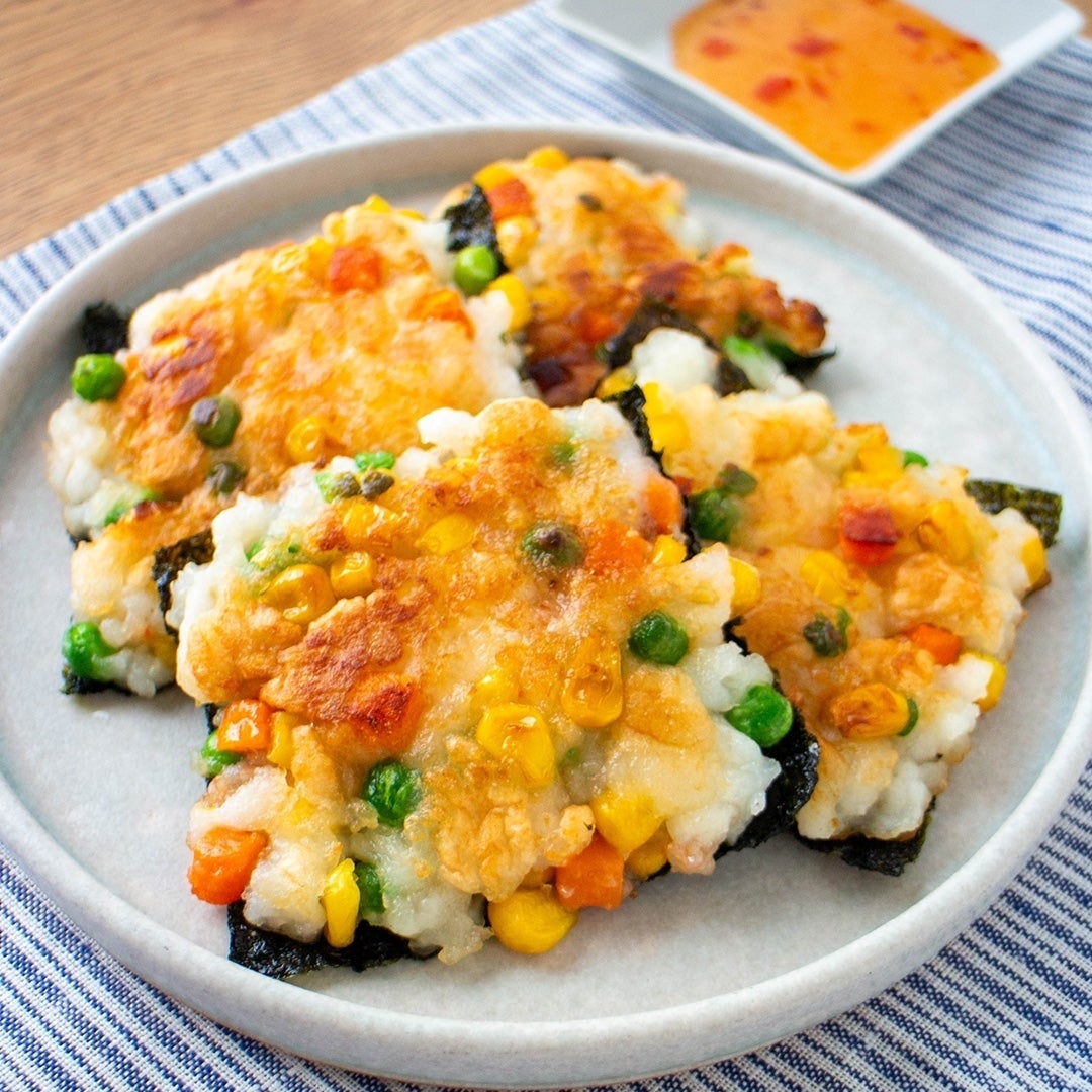 お皿に盛られた野菜と魚介入りの韓国風チヂミ、ソース付き。