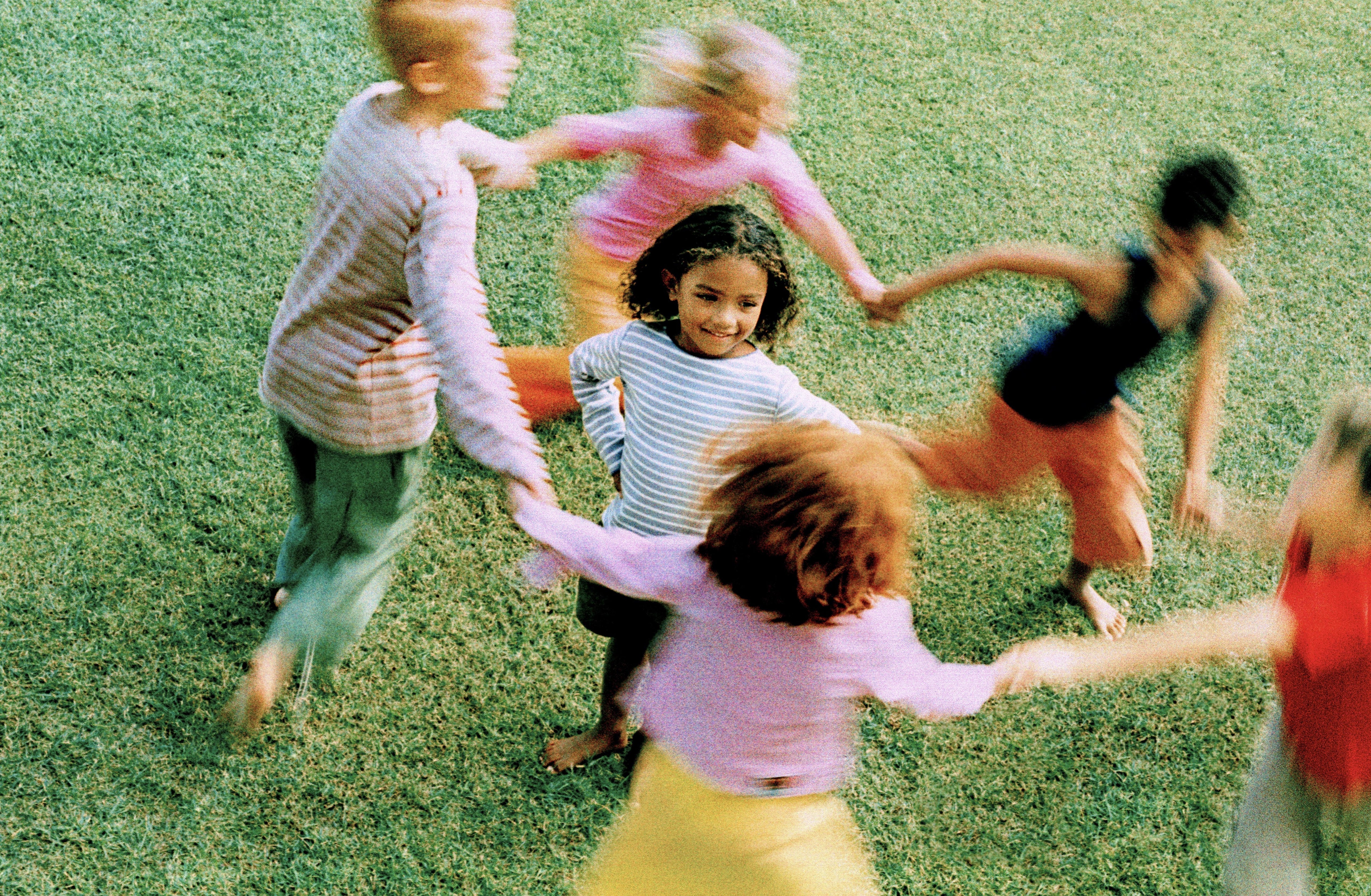Children holding hands, playing in a circle on grass