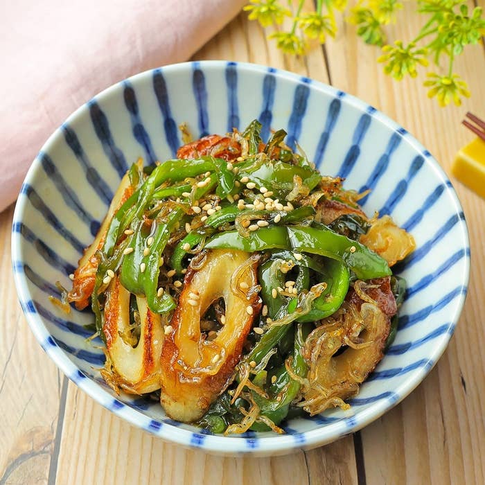 縞模様の器に盛られた焼き魚の切り身と青唐辛子の料理。ゴマがトッピングされています。