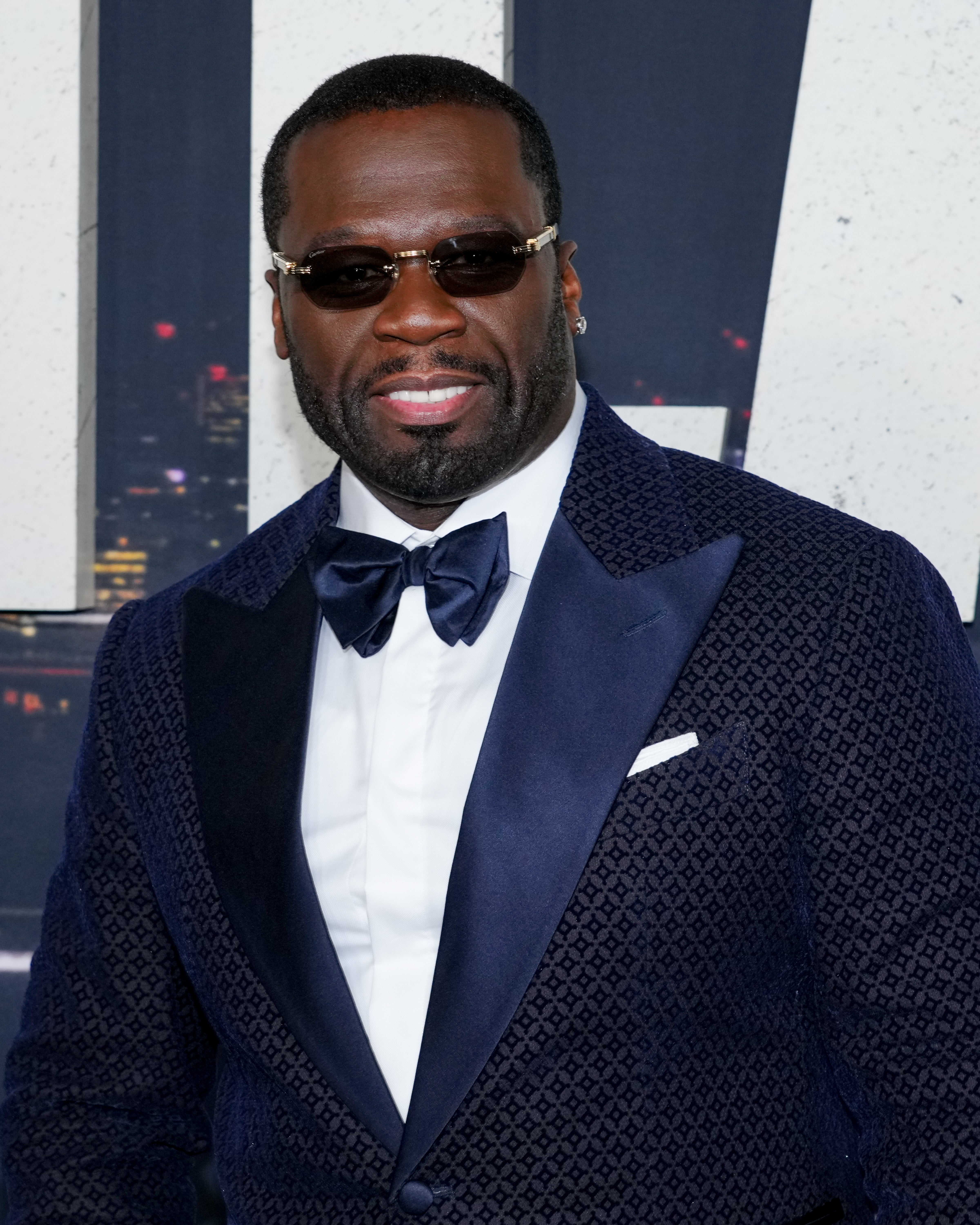 Man in textured suit with satin bow tie and sunglasses attending a formal event