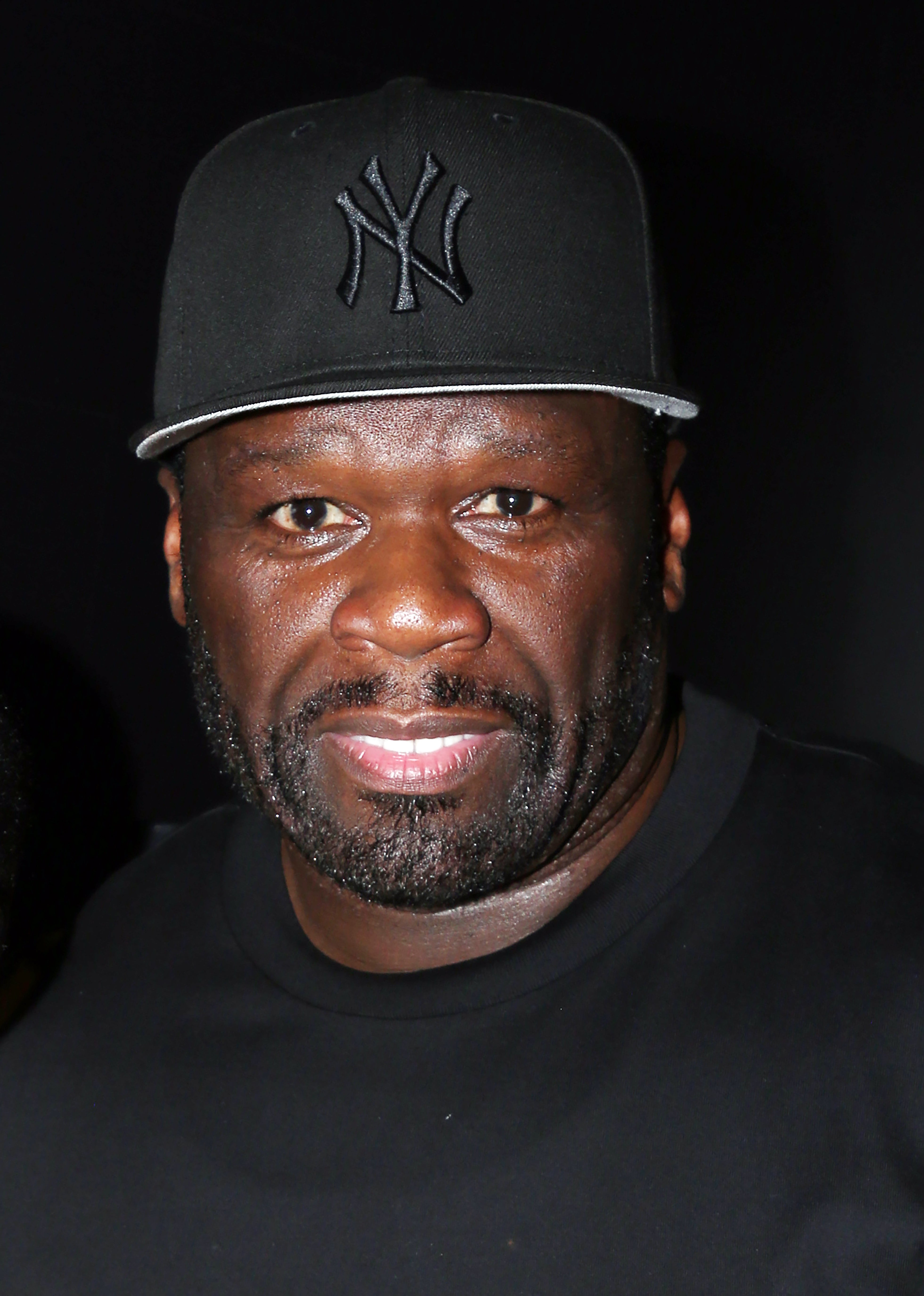 Man wearing a baseball cap with an emblem, looking at the camera
