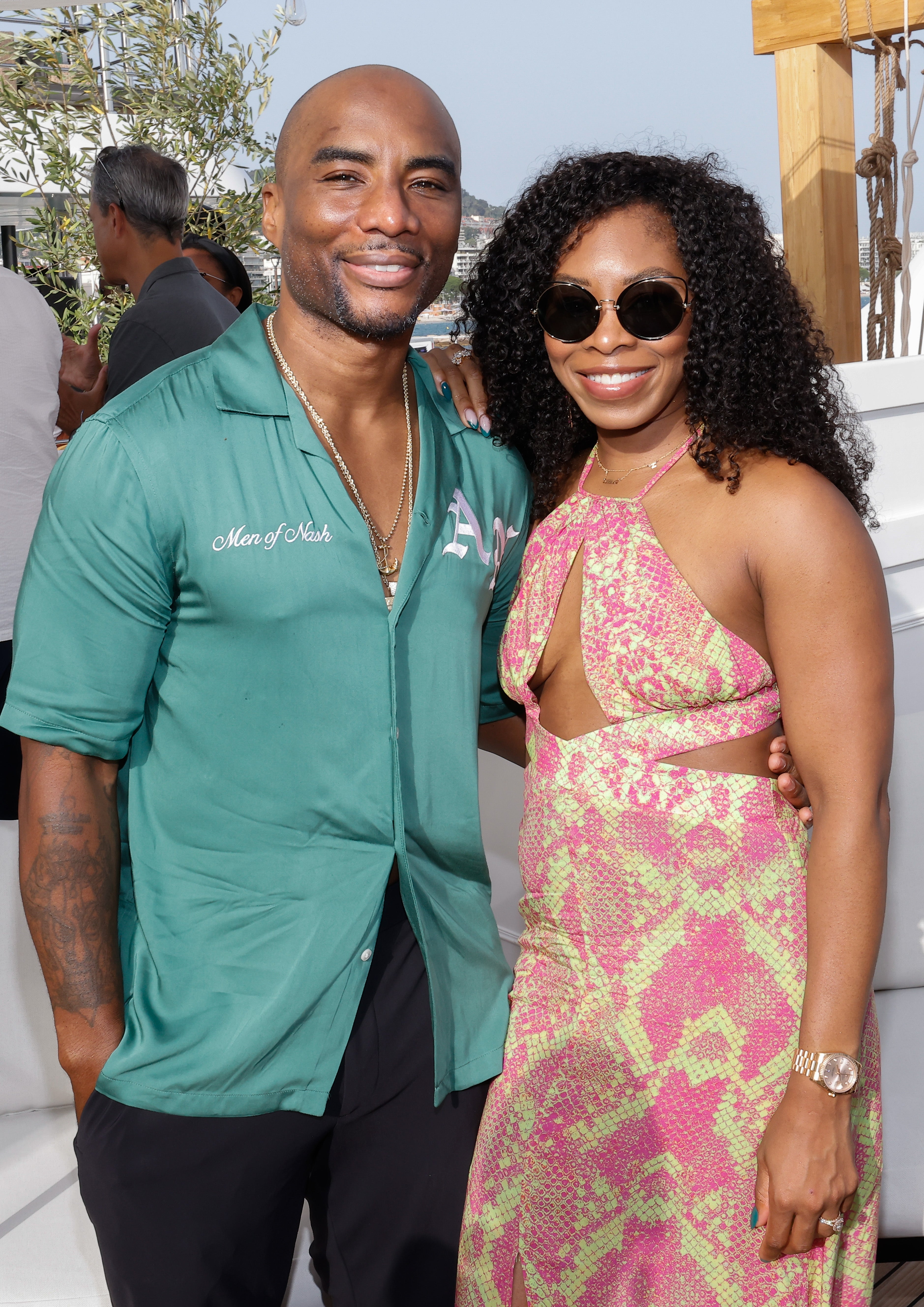 I don't know who these people are. A person in a green shirt stands beside a person in a patterned cut-out dress at an outdoor event